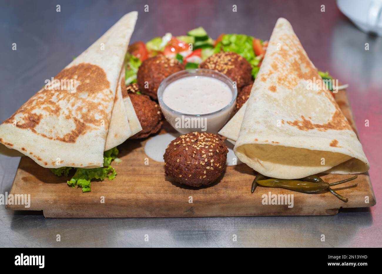 Présentation du plat libanais du Moyen-Orient Falafel sur une assiette en bois. tortilla, salade de légumes et sauce tahini. Banque D'Images