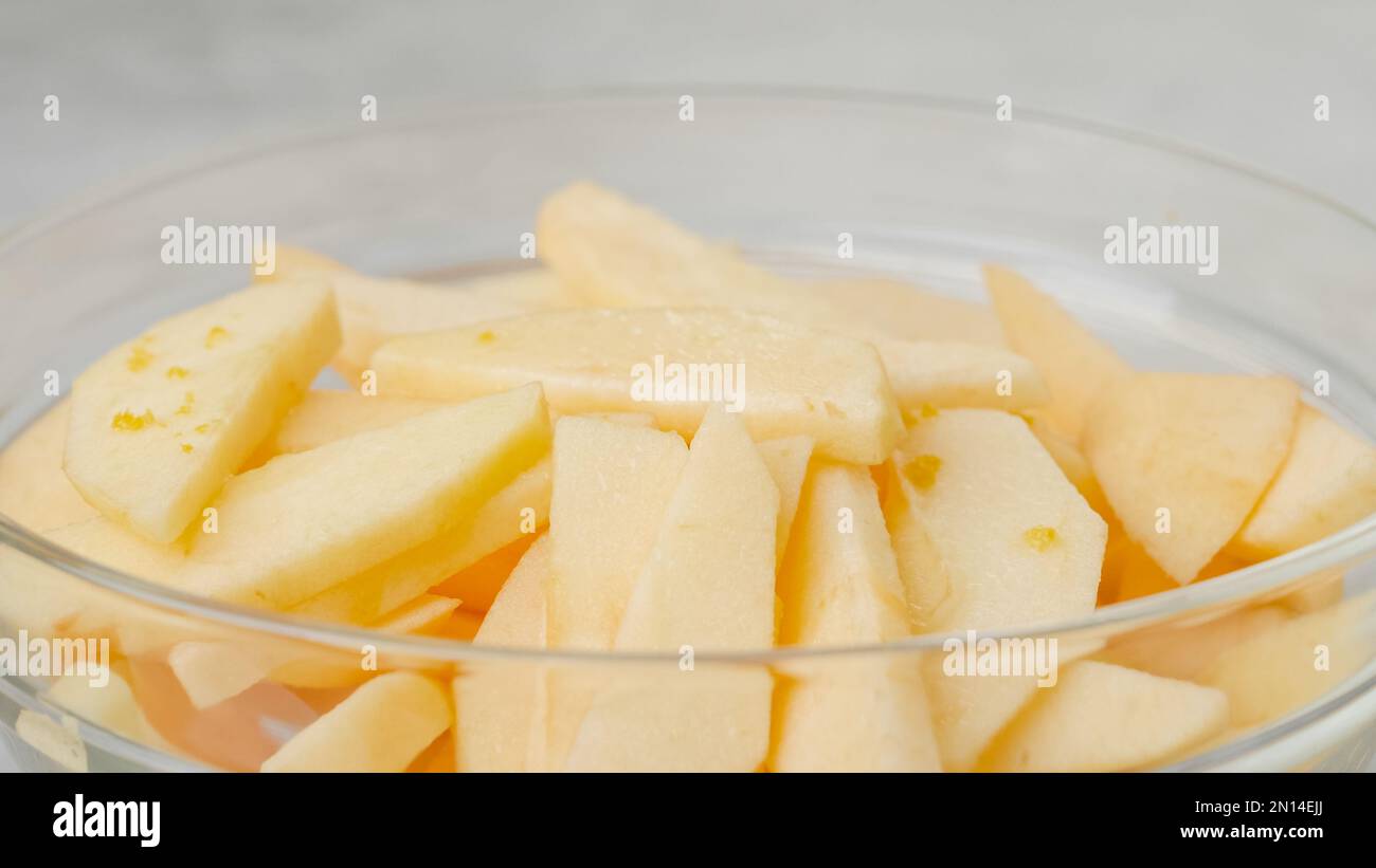 Tranches de pomme dans un bol en verre. Garniture de tranches de jus de citron et de zeste de citron. Recette de gâteau aux pommes Banque D'Images