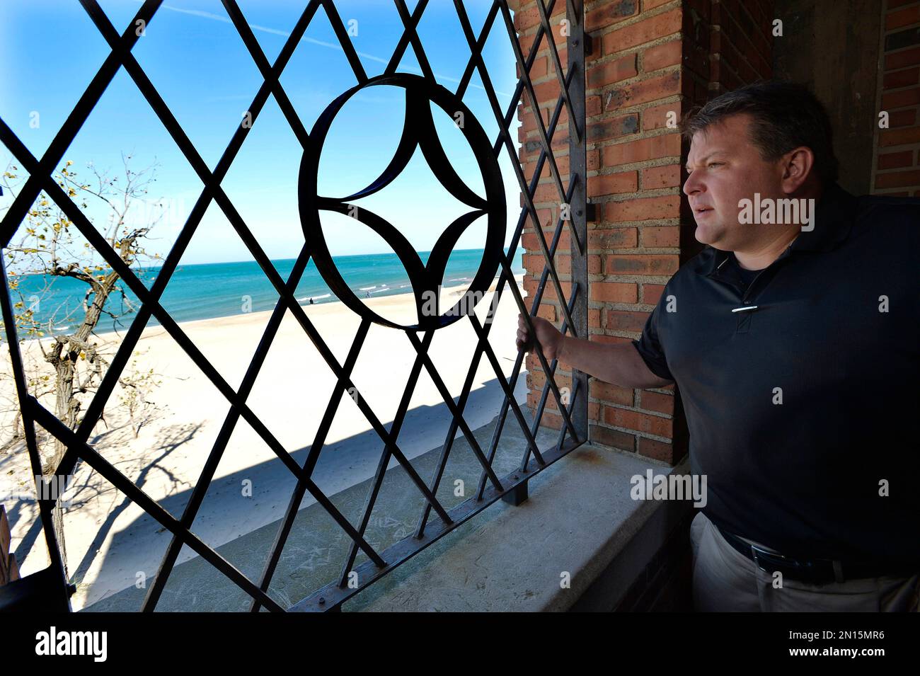 In this Oct. 19, 2015 photo, developer Chuck Williams, a state Republican Party official, looks at the Lake Michigan shoreline through a window in the dilapidated beachfront pavilion at Indiana Dunes State Park in Chesterton, Ind., that he plans to rehabilitate. Williams is warning that Indiana could owe him millions of dollars if officials scuttle his contract to bring fine dining, a banquet hall and bar to a lakefront state park surrounded by the state’s towering dunes. (AP Photo/Paul Beaty) Banque D'Images