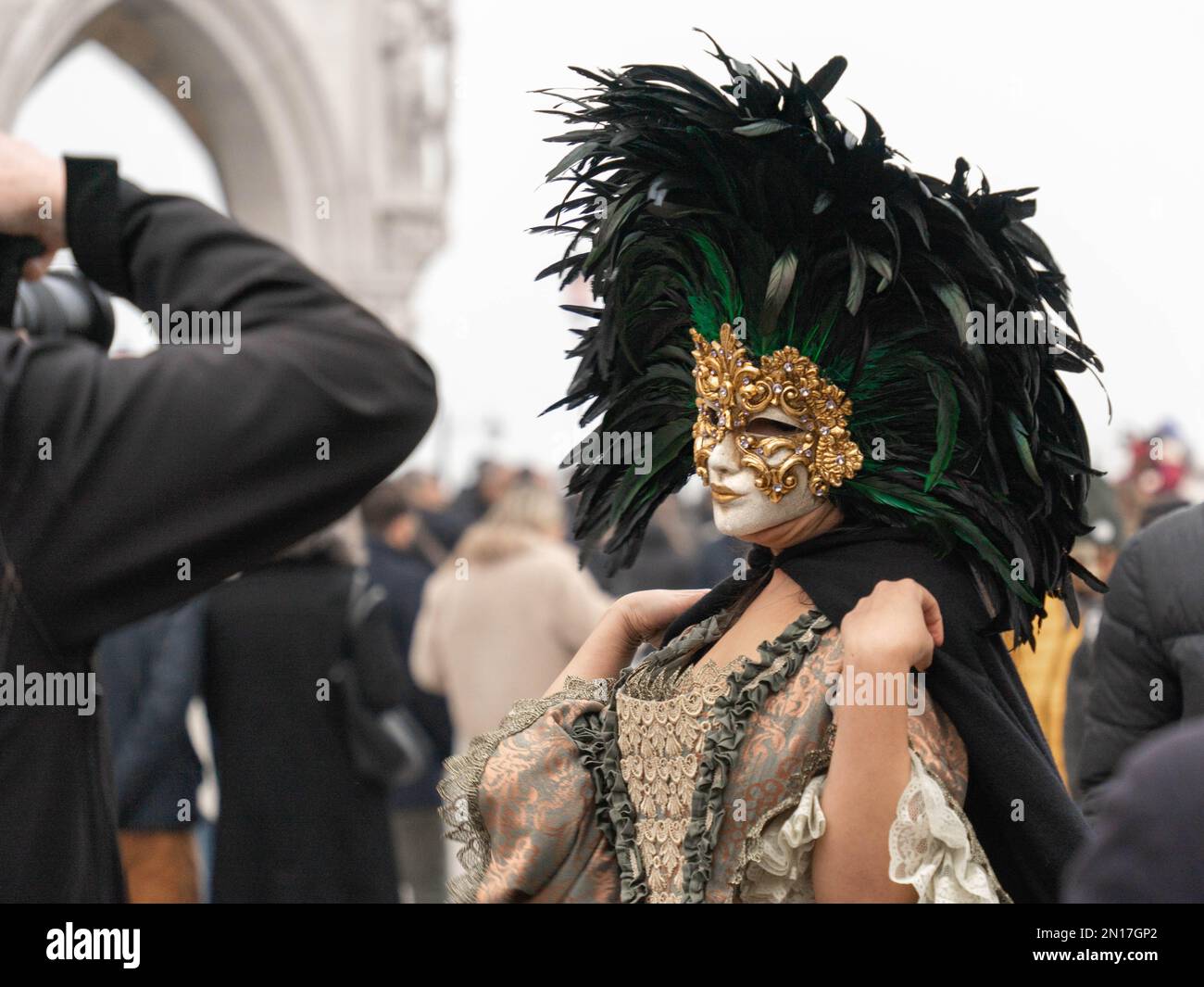 Carnaval de la Vinèce. Une femme en costume d'époque, portant un masque de carnaval bordé d'un cercle de plumes noires élevées, pose à un photographe Banque D'Images