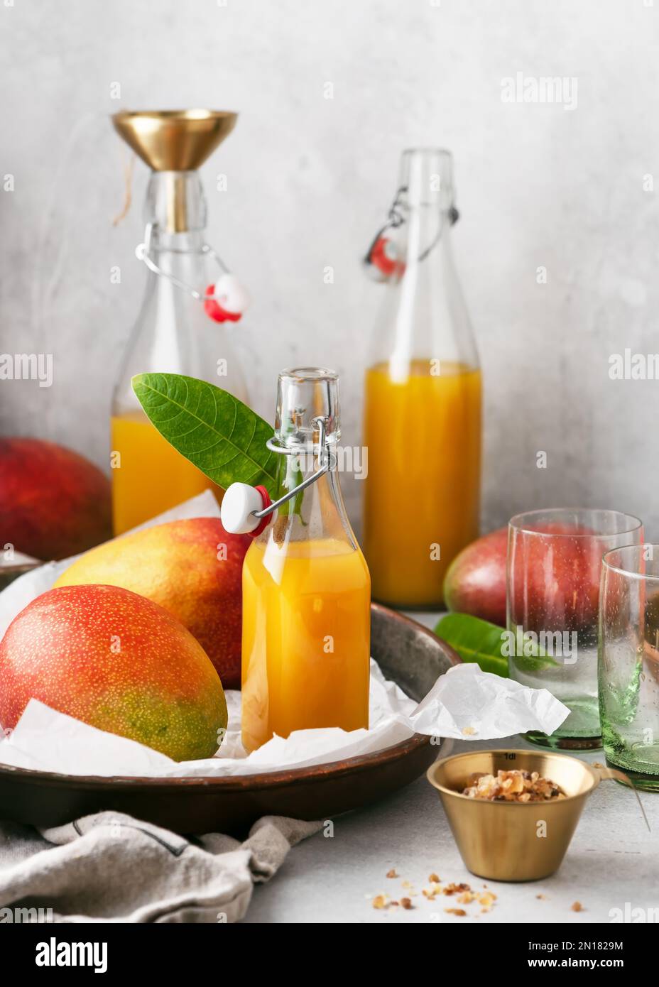 Bouteilles en verre de jus de fruits frais et plaque métallique rustique avec mangues biologiques et sucre caniche. Concept d'alimentation saine. Banque D'Images