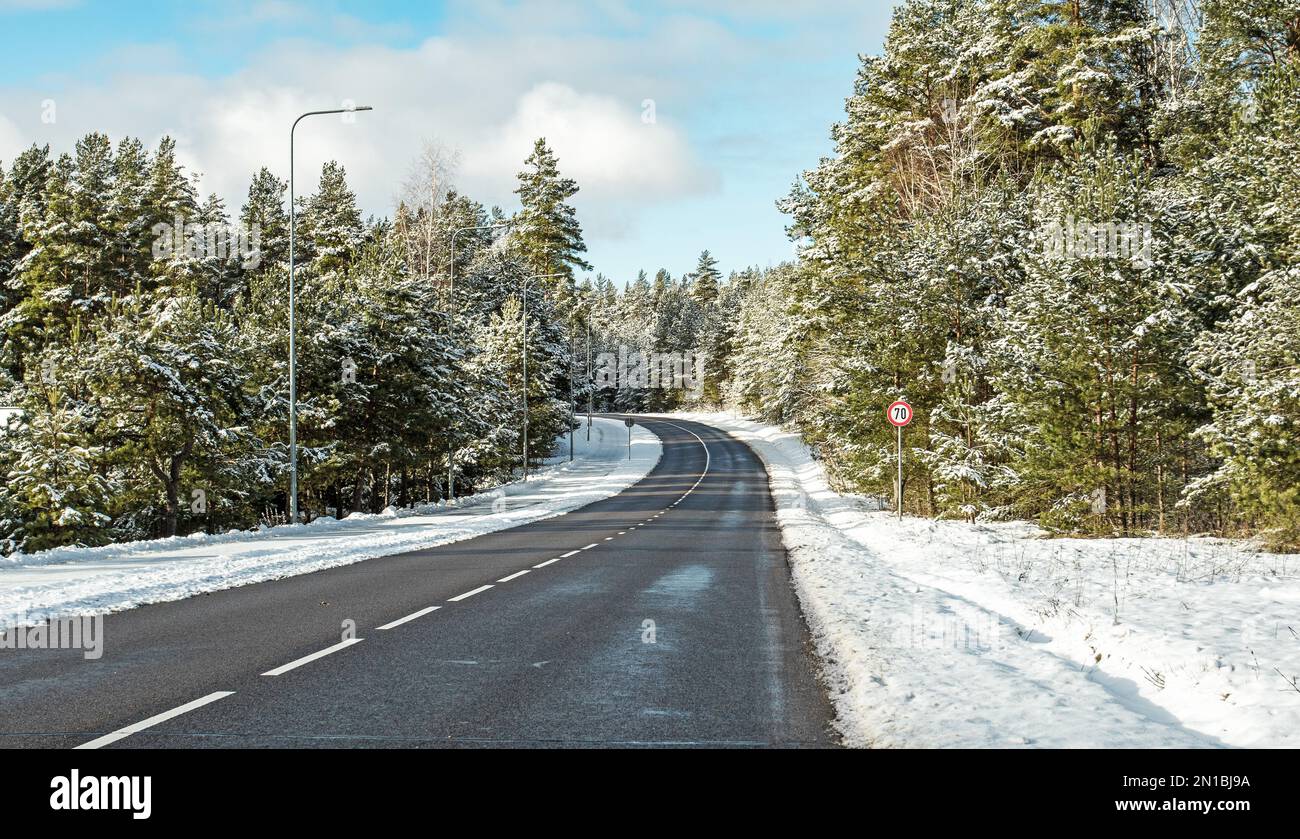 Paysage d'hiver par jour ensoleillé. L'autoroute de l'asphalte va dans une forêt de pins enneigés. Banque D'Images