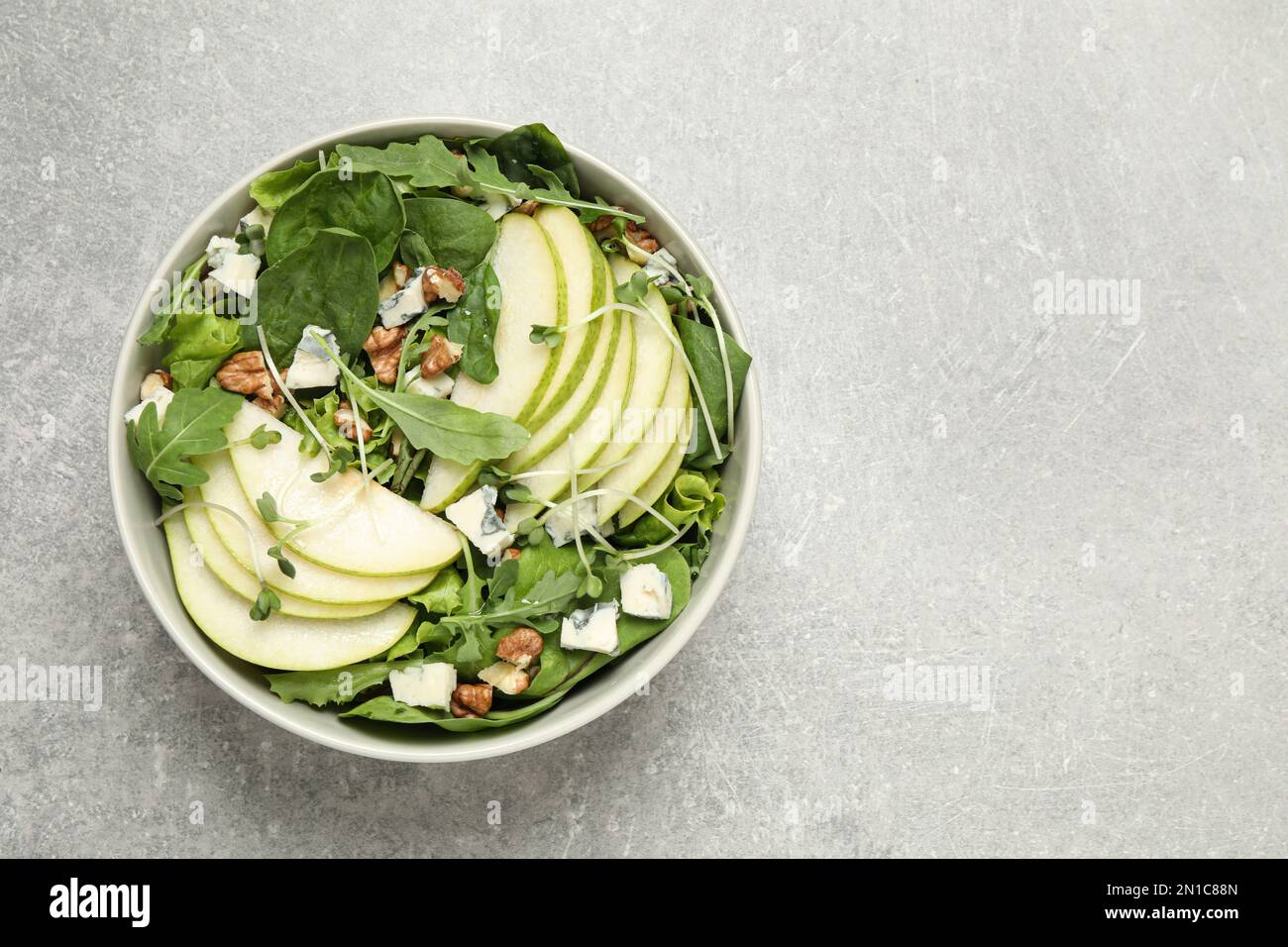 Salade savoureuse avec des tranches de poire sur une table gris clair, vue du dessus. Espace pour le texte Banque D'Images