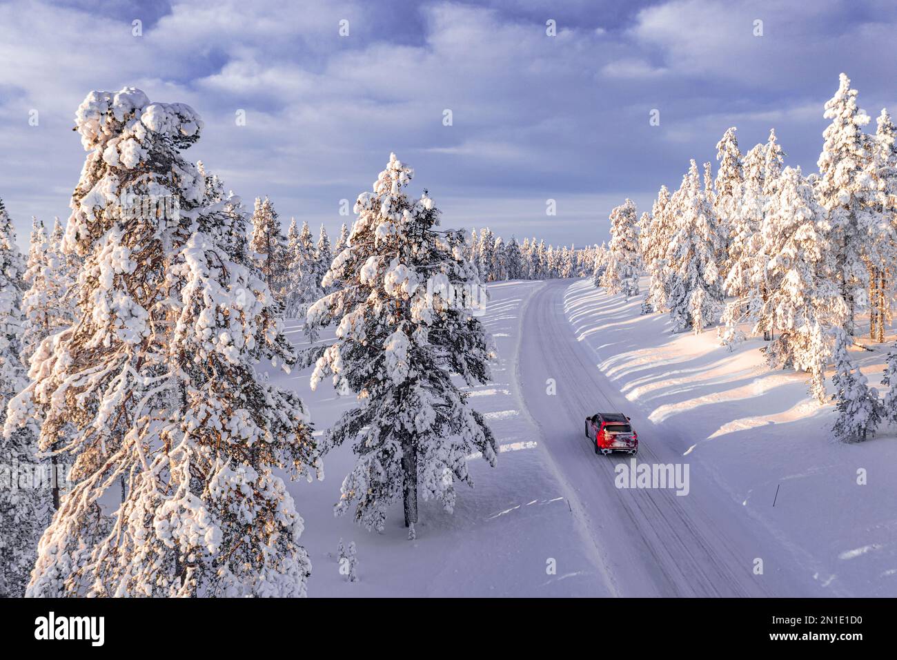 Vue en grand angle d'un véhicule tout-terrain roulant sur une piste glacée parmi les arbres couverts de neige, Kangos, Laponie, Suède, Scandinavie, Europe Banque D'Images