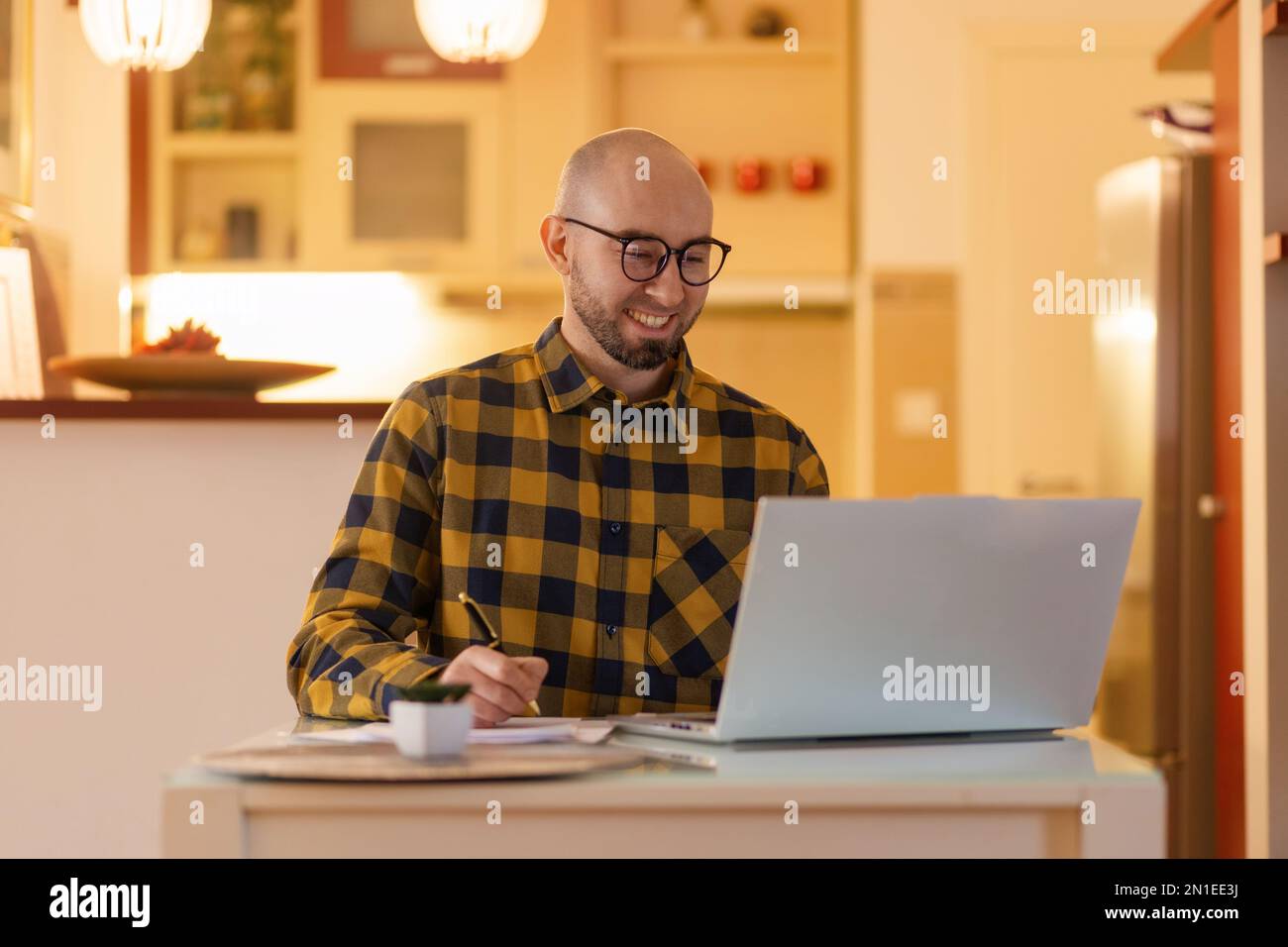 Portrait d'un jeune homme du Caucase portant des lunettes souriant et travaillant sur un ordinateur portable. Travailleur utilisant un ordinateur. Concept de travail à distance et freelance. Banque D'Images