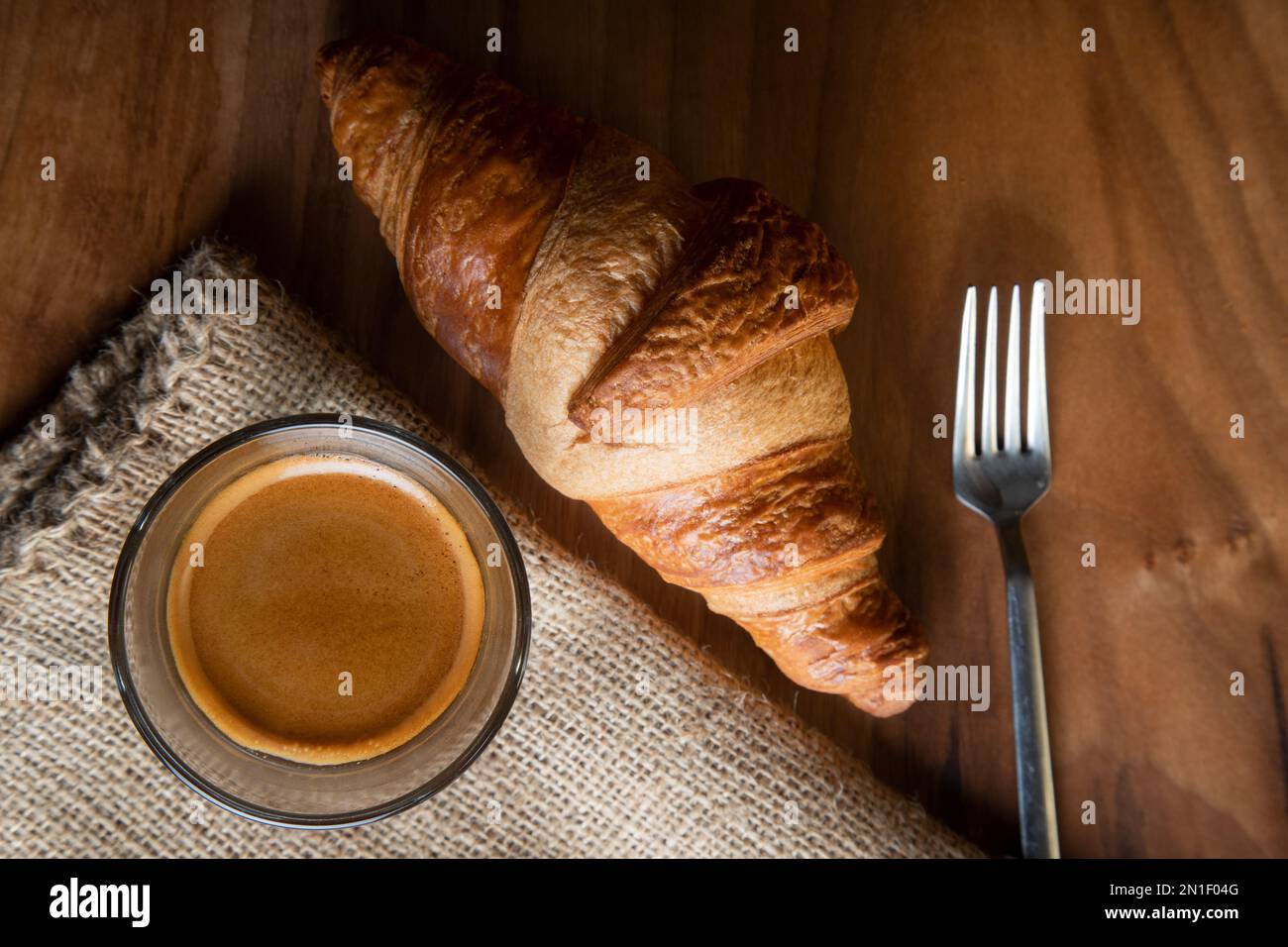 Croissant avec espresso dans une tasse blanche sur une table en bois Banque D'Images