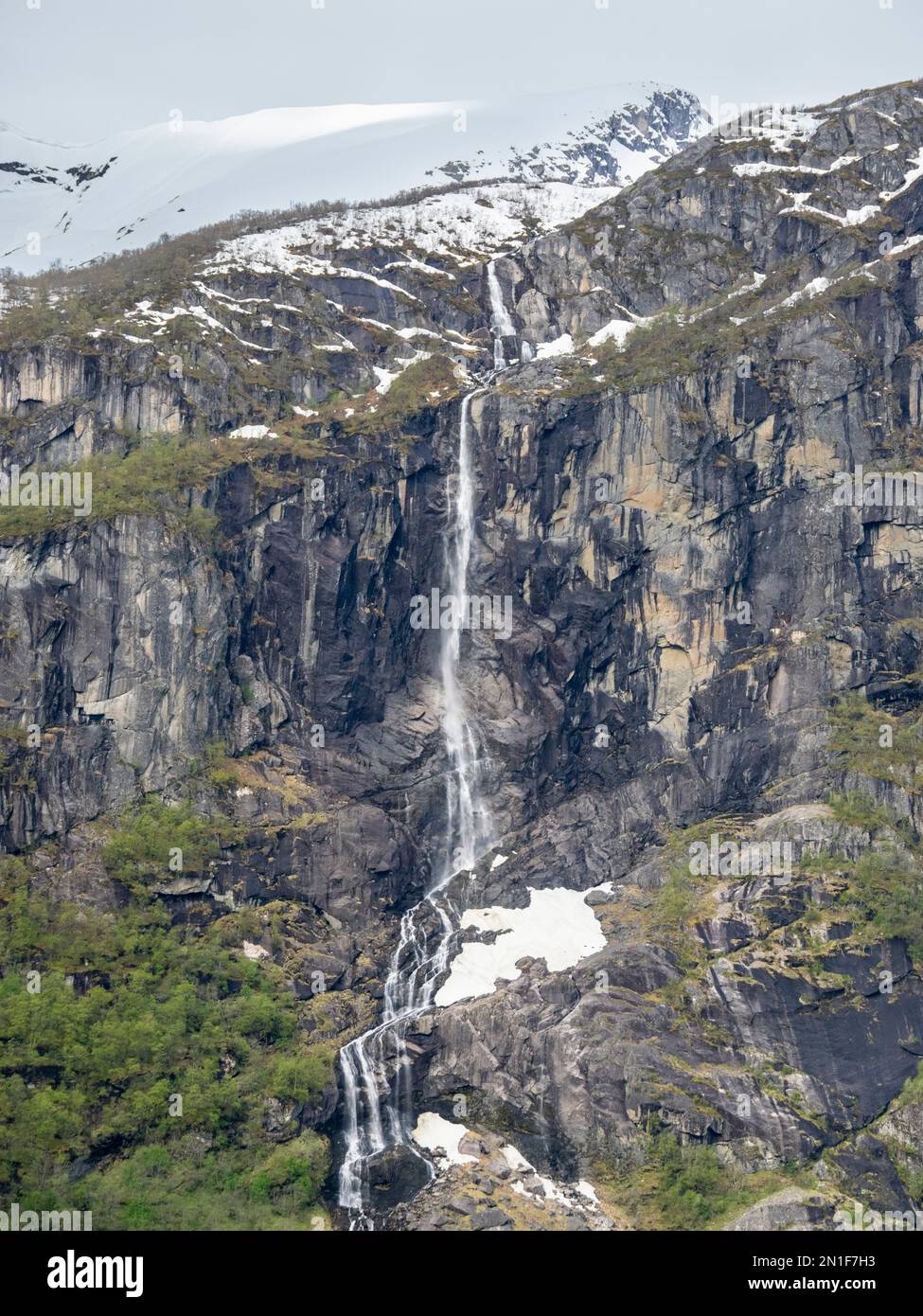 Une vue sur une chute d'eau sur le mur escarpé des montagnes avec le glacier Myklebustbreen au sommet, Vestland, Norvège, Scandinavie, Europe Banque D'Images