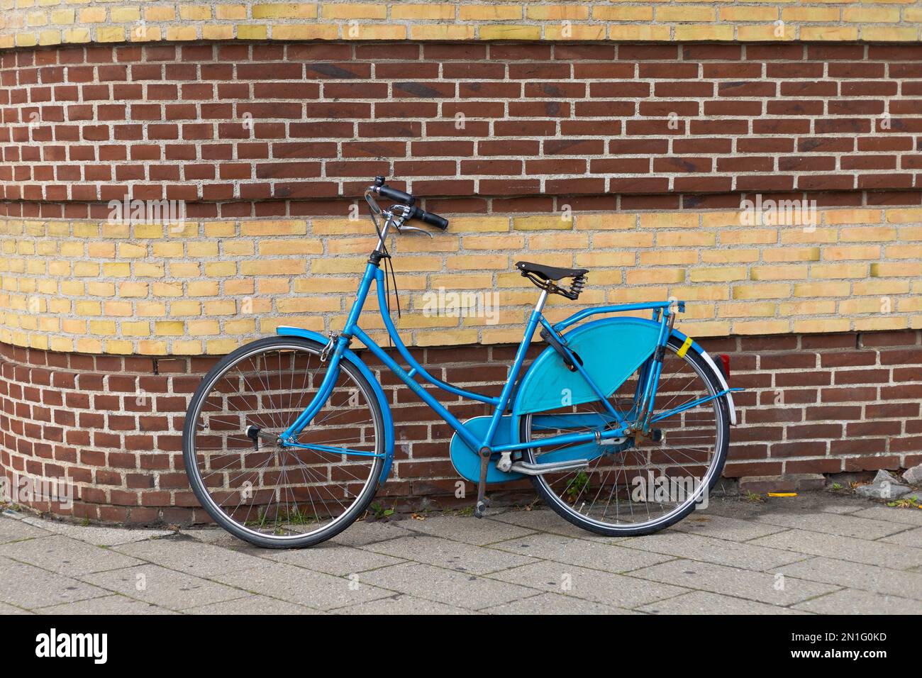 vélo bleu appuyé contre un mur de briques Banque D'Images
