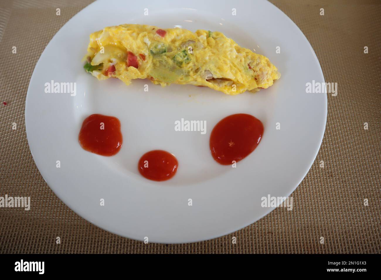 Omelette au petit déjeuner moelleuse avec sauce sur une assiette blanche Banque D'Images
