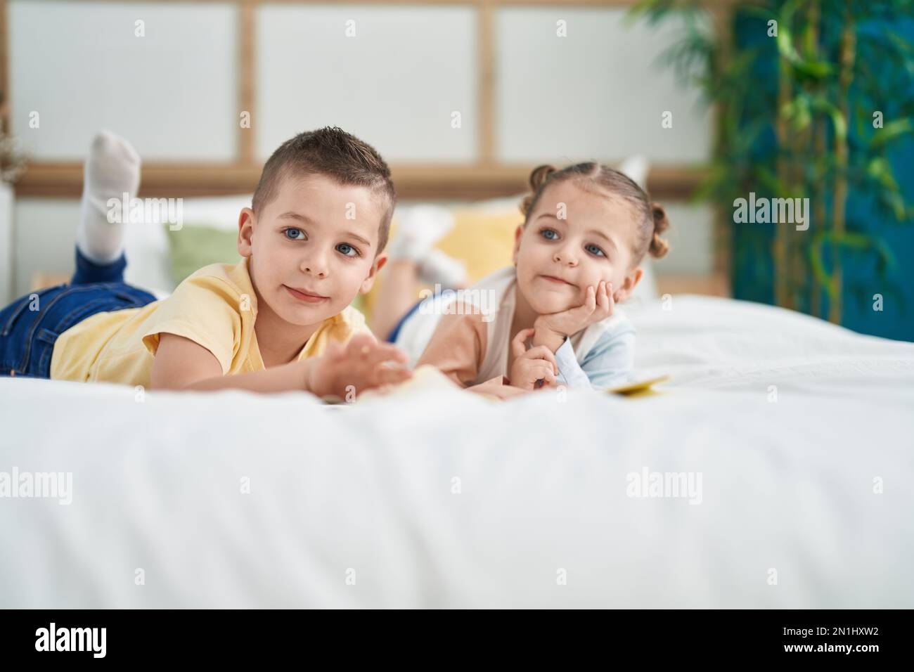 Deux enfants lisant un livre d'histoire allongé sur le lit dans la chambre Banque D'Images