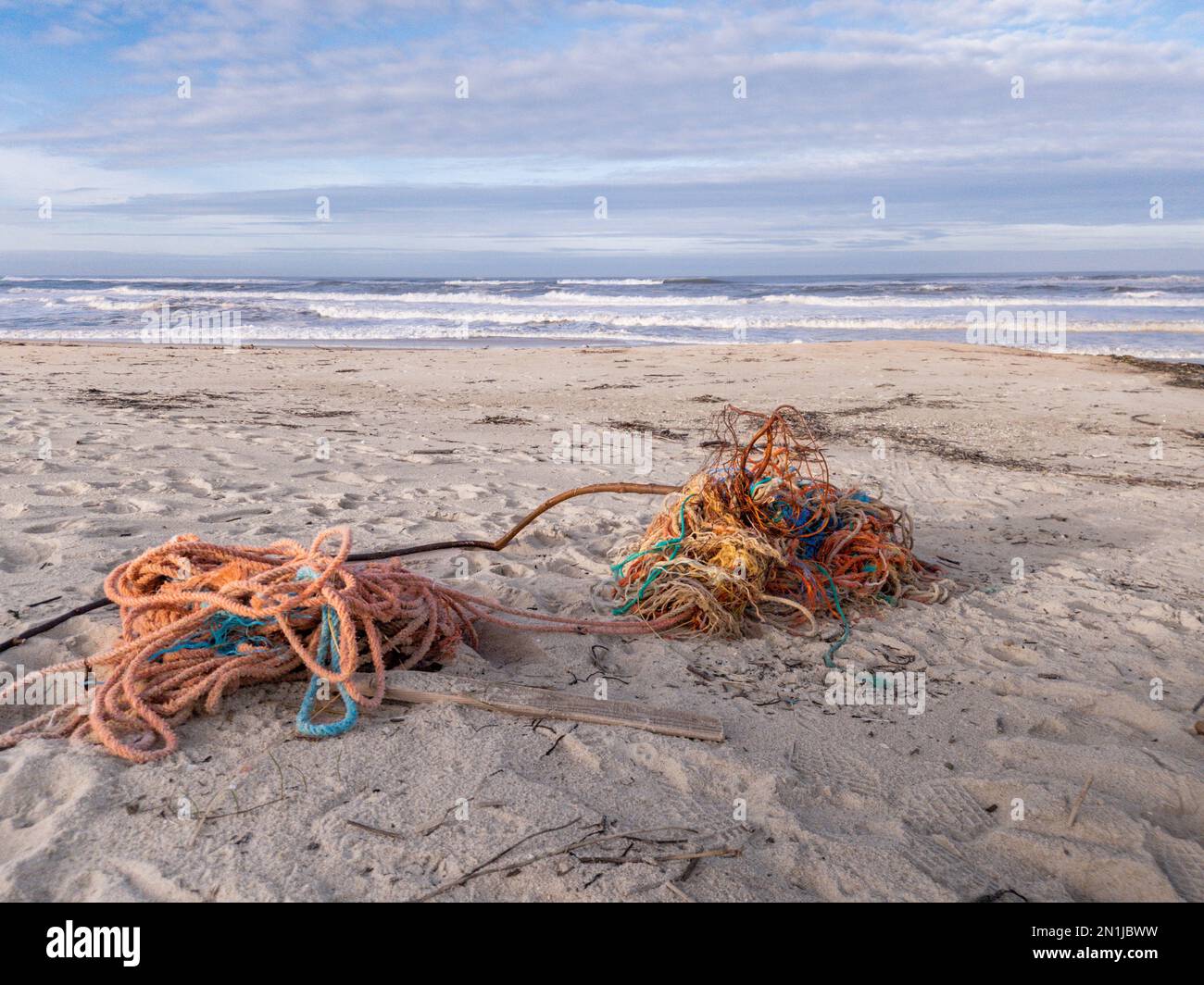 Des cordes, des filets et des épaves de bateaux de pêche emmêlés ont été lavés sur le sable d'une plage sale au Portugal avec l'océan et le ciel en arrière-plan Banque D'Images