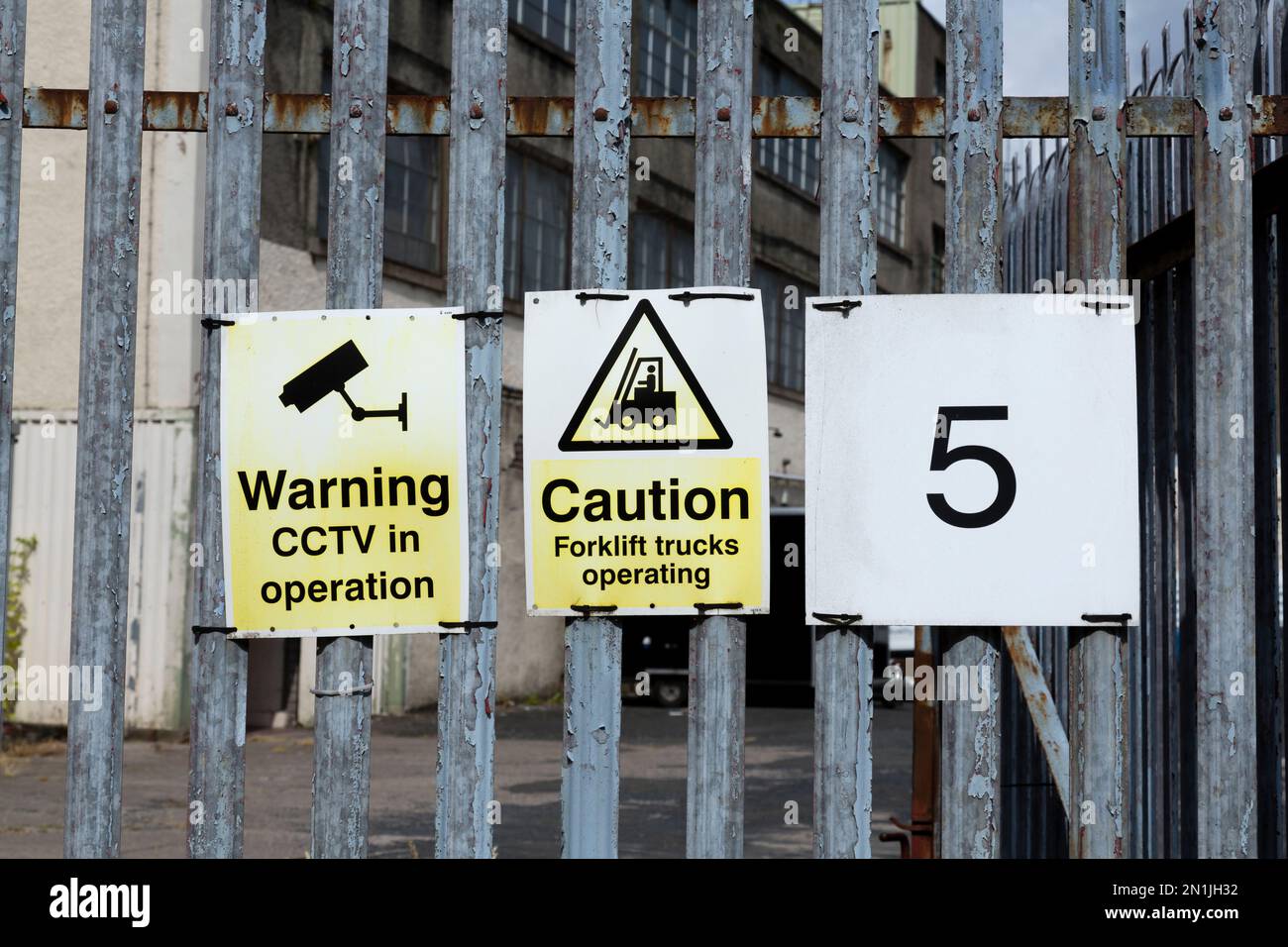 Avertissement CCTV en fonctionnement et attention chariots élévateurs signes d'utilisation sur la clôture extérieure d'un bâtiment industriel, Écosse, Royaume-Uni, Europe Banque D'Images