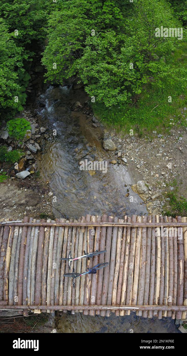 Vue aérienne par drone d'une paire de deux vélos assis sur une passerelle à partir de troncs d'arbres crus. La rivière Cibin coule sous le pont, entrant dans les bois Banque D'Images