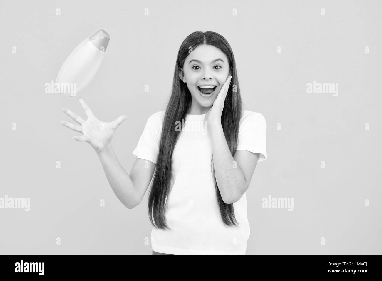 Portrait heureux de l'enfant avec après-shampooing. Soins cosmétiques quotidiens. L'adolescent de 12, 13, 14 ans tient une bouteille de soins pour les cheveux et la peau. Beauté Banque D'Images