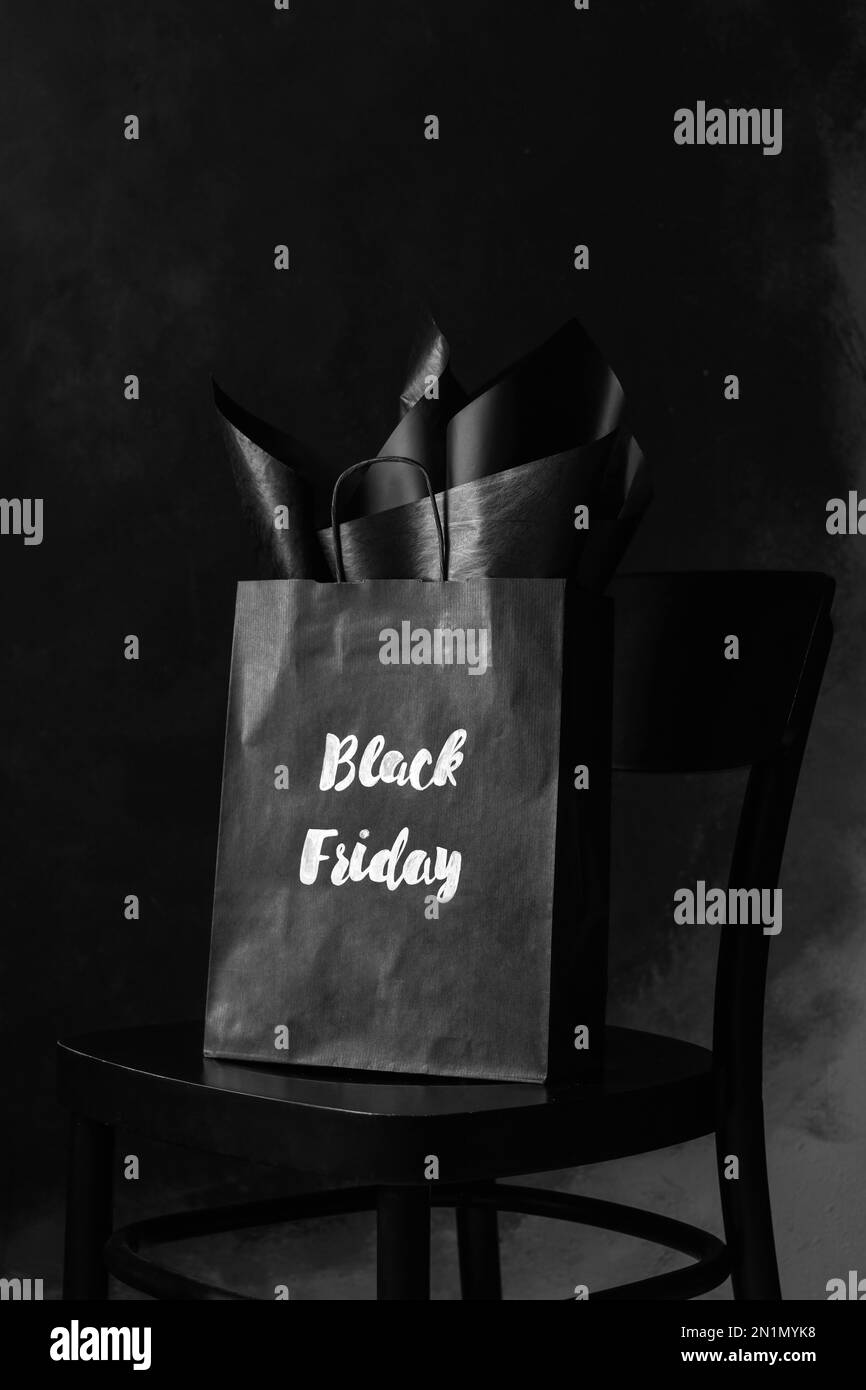 Sac de shopping avec des mots « Black Friday » sur une chaise sur fond sombre Banque D'Images