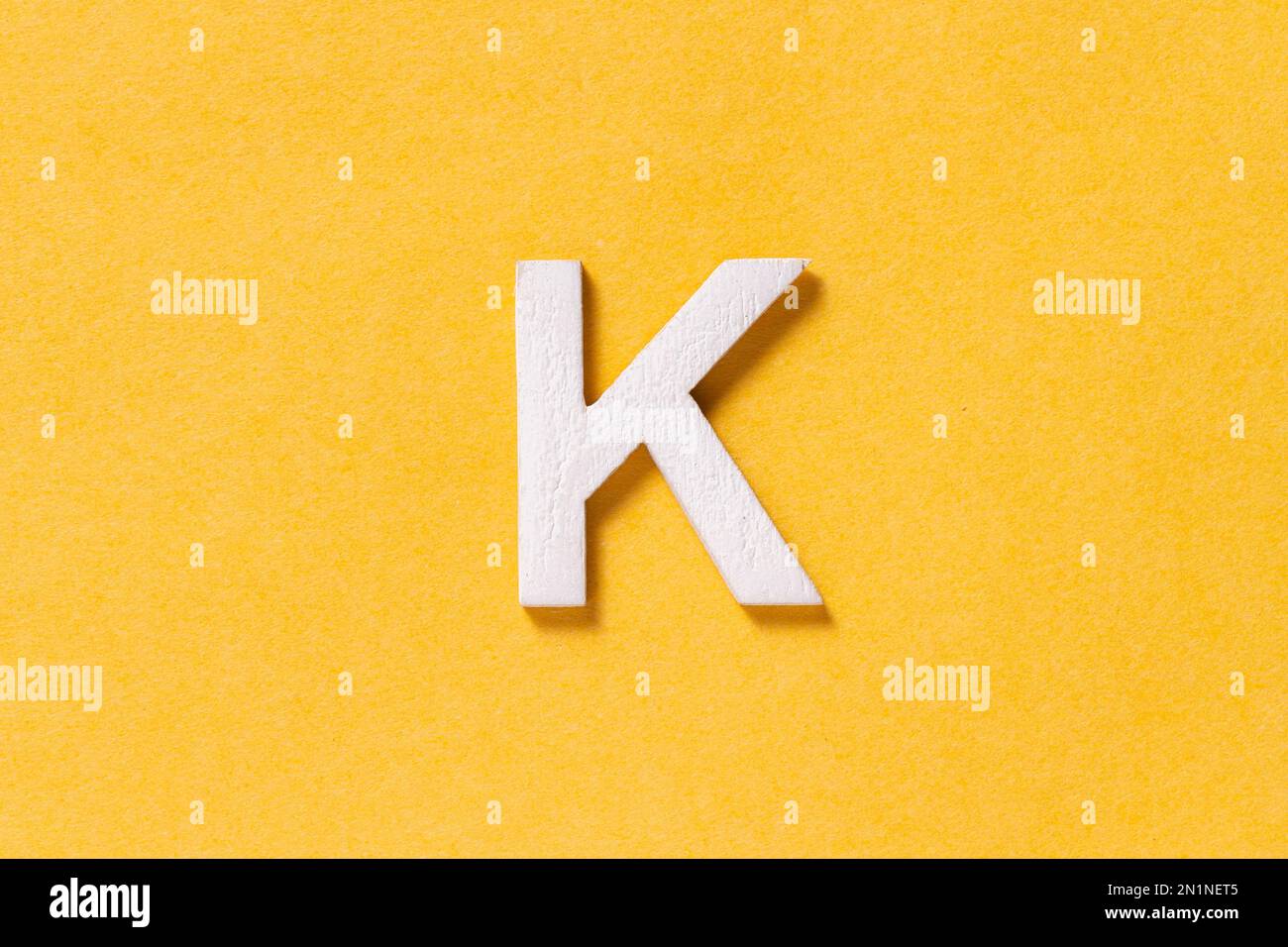 Lettre K de l'alphabet isolée sur fond jaune, vue du dessus Banque D'Images