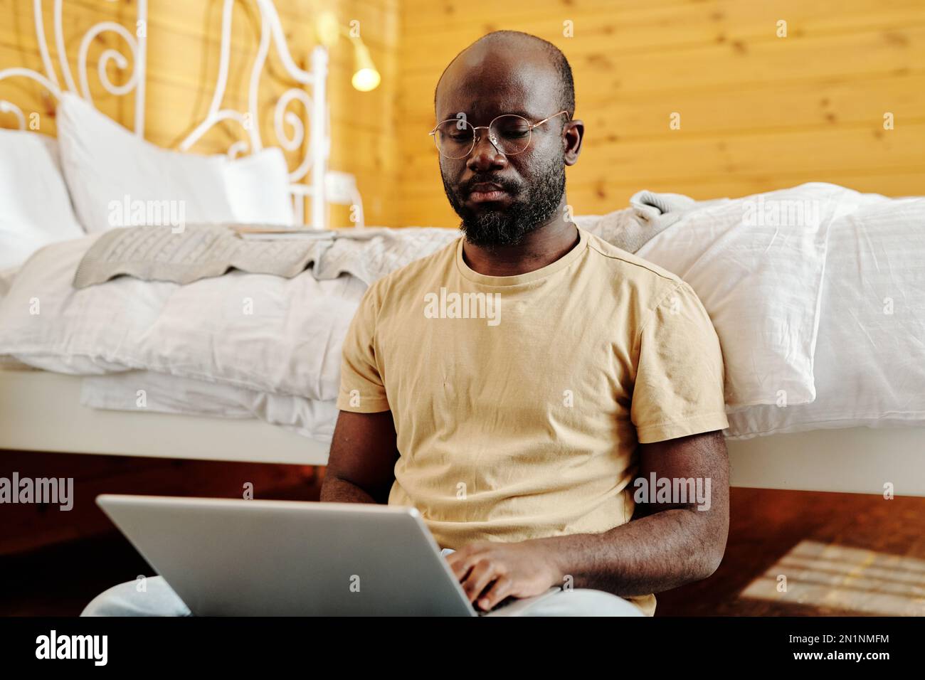 Homme indépendant sérieux avec ordinateur portable assis au sol d'un lit  double dans la chambre et l'organisation de son travail ou la recherche de  données en ligne Photo Stock - Alamy