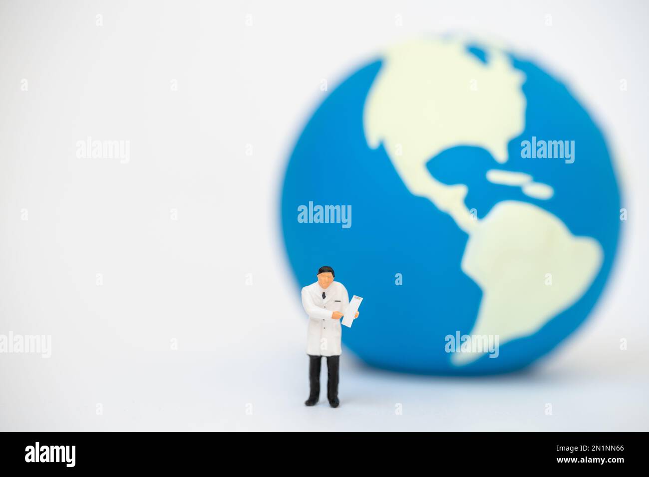 Concept global Healthcare. Médecin miniature figure personnes avec le presse-papiers de patient debout avec mini boule de monde comme arrière-plan. Banque D'Images