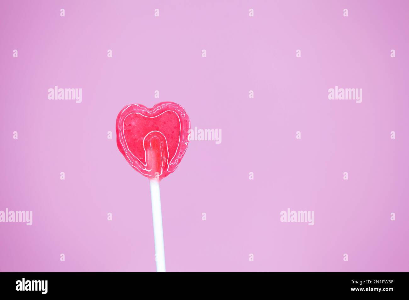 Lollipop de sucre en forme de coeur sur fond rose Banque D'Images