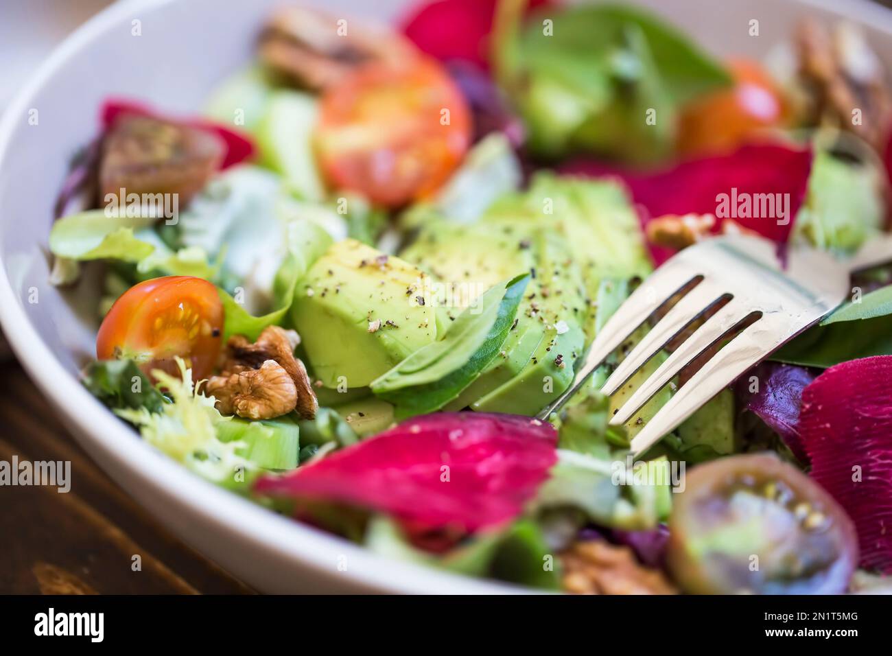 Salade d'été fraîche avec avocat, laitue, betterave, noix et graines. Salade végétalienne saine d'été sur une table en bois, manger propre Banque D'Images