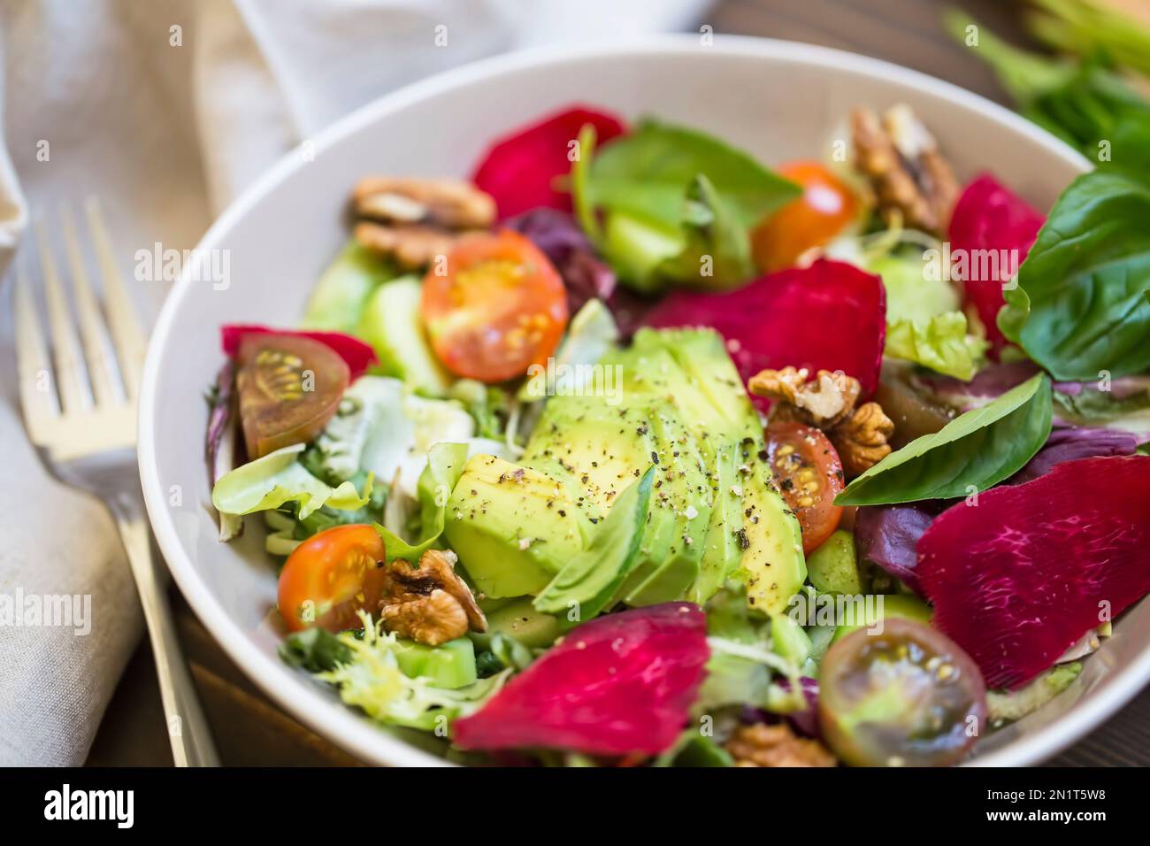 Salade d'été fraîche avec avocat, laitue, betterave, noix et graines. Salade végétalienne saine d'été sur une table en bois, manger propre Banque D'Images