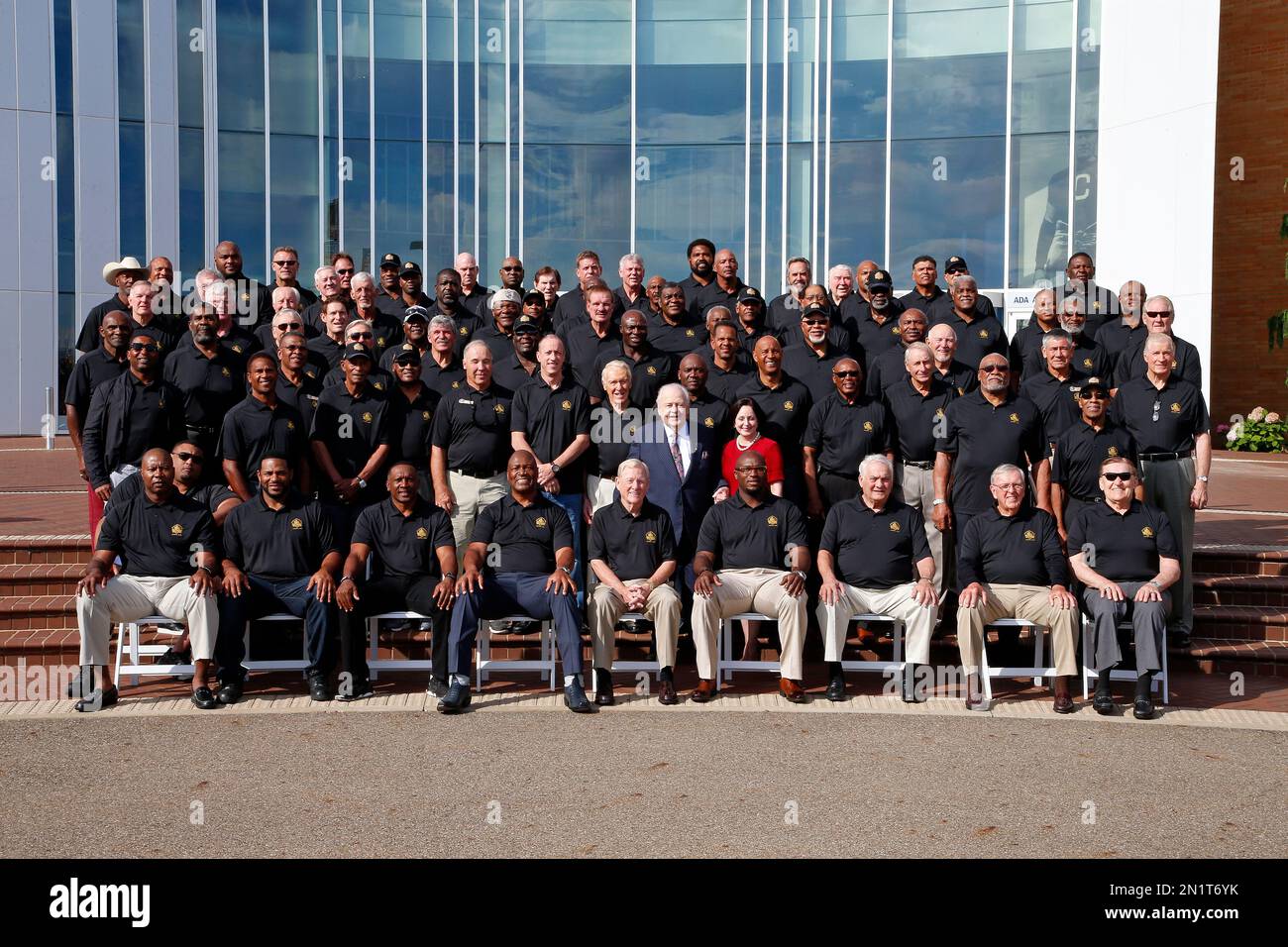 New Orleans Saints owner Tom Benson, center, and his wife Gayle, in red, pose with the Pro Football Hall of Fame 2015 inductees and Pro Football Hall of Famers for a group photo on the steps of the Pro Football Hall of Fame in Canton, Ohio, Friday, Aug. 7, 2015. (AP Photo/Gene J. Puskar) Banque D'Images