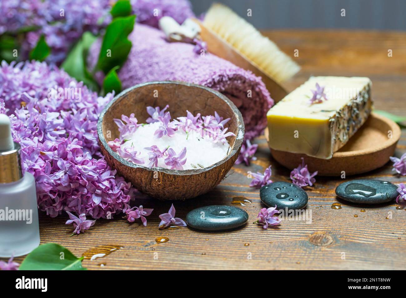 Spa avec savon naturel, huile pure essentielle au lilas, sel de mer et pierres de massage avec serviettes en coton doux pour se faire dorloter Banque D'Images