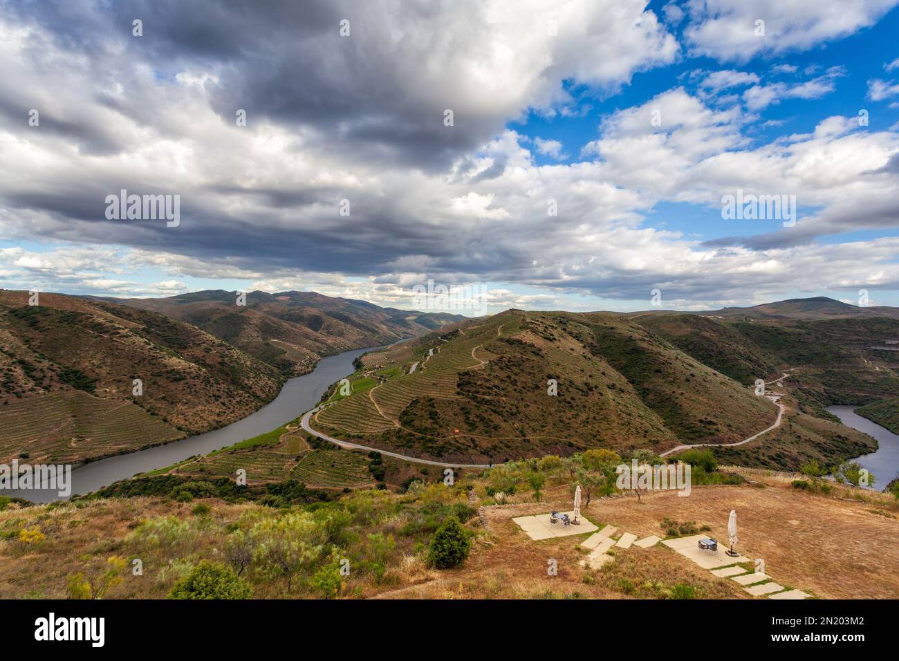 La vallée du Douro avec sa rivière et ses vignobles cultivés en terrasses sur les flancs de montagne. Superbe ciel nuageux reflété dans les eaux de la rivière. Banque D'Images