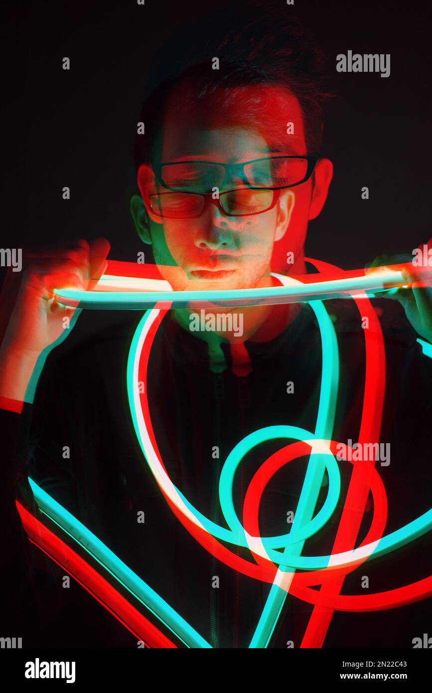 Glitch Double Exposure Portrait futuriste en beau jeune hipster homme avec des lunettes tendance sur enveloppé de ruban lumineux au néon Banque D'Images