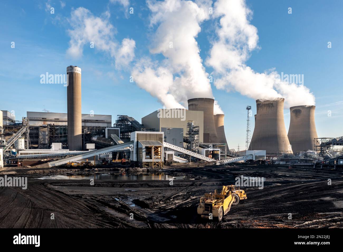 Une usine lourde raclant le charbon d'une cheminée de combustible fossile dans une grande centrale au charbon pour brûler pour produire de l'électricité non renouvelable Banque D'Images