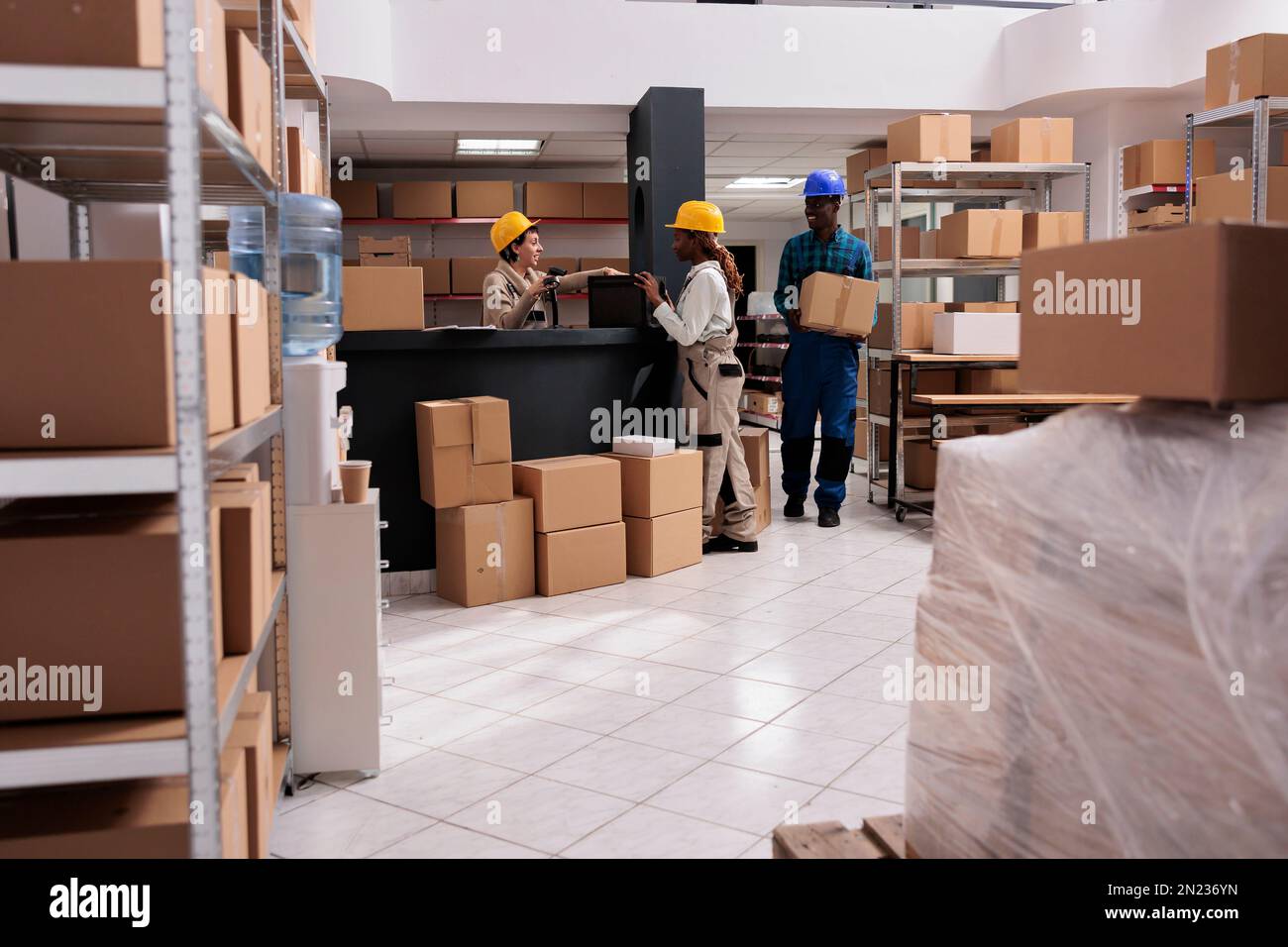 Les employés de l'entrepôt numérisent les marchandises au bureau  d'enregistrement des colis, en tenant une boîte en carton pour l'emballage  des commandes du client. Travailleurs de magasins caucasiens et africains  américains préparant
