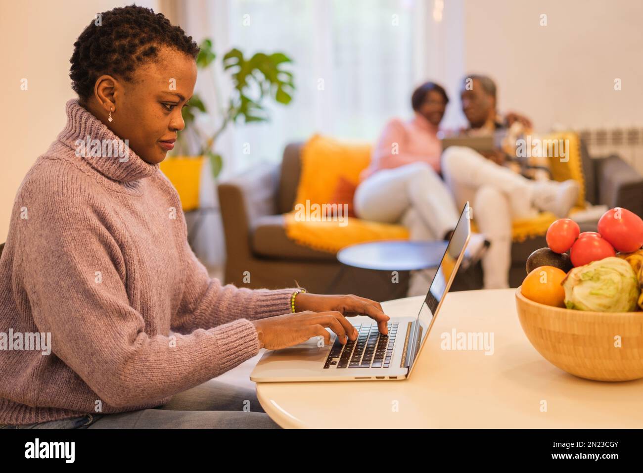 Une jeune femme travaillant à distance pour être en mesure de prendre soin de ses parents retraités âgés. Concept: Réconciliation, travail à la maison, famille Banque D'Images