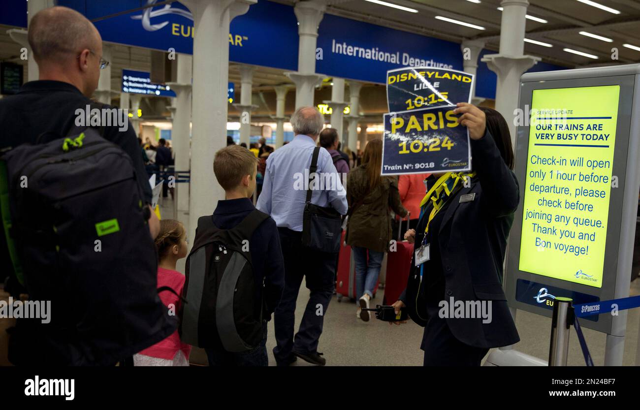 Passengers walk past a member of Eurostar staff holding up train times and destinations at the departure gates at St Pancras train station in London Wednesday, June 24, 2015. Many passengers had rebooked after disruption yesterday. All trains and many ferry services between Britain and France were cut off Tuesday by striking port workers, stranding hundreds of trucks and thousands of passengers on both sides of the English Channel.(AP Photo/Alastair Grant) Banque D'Images