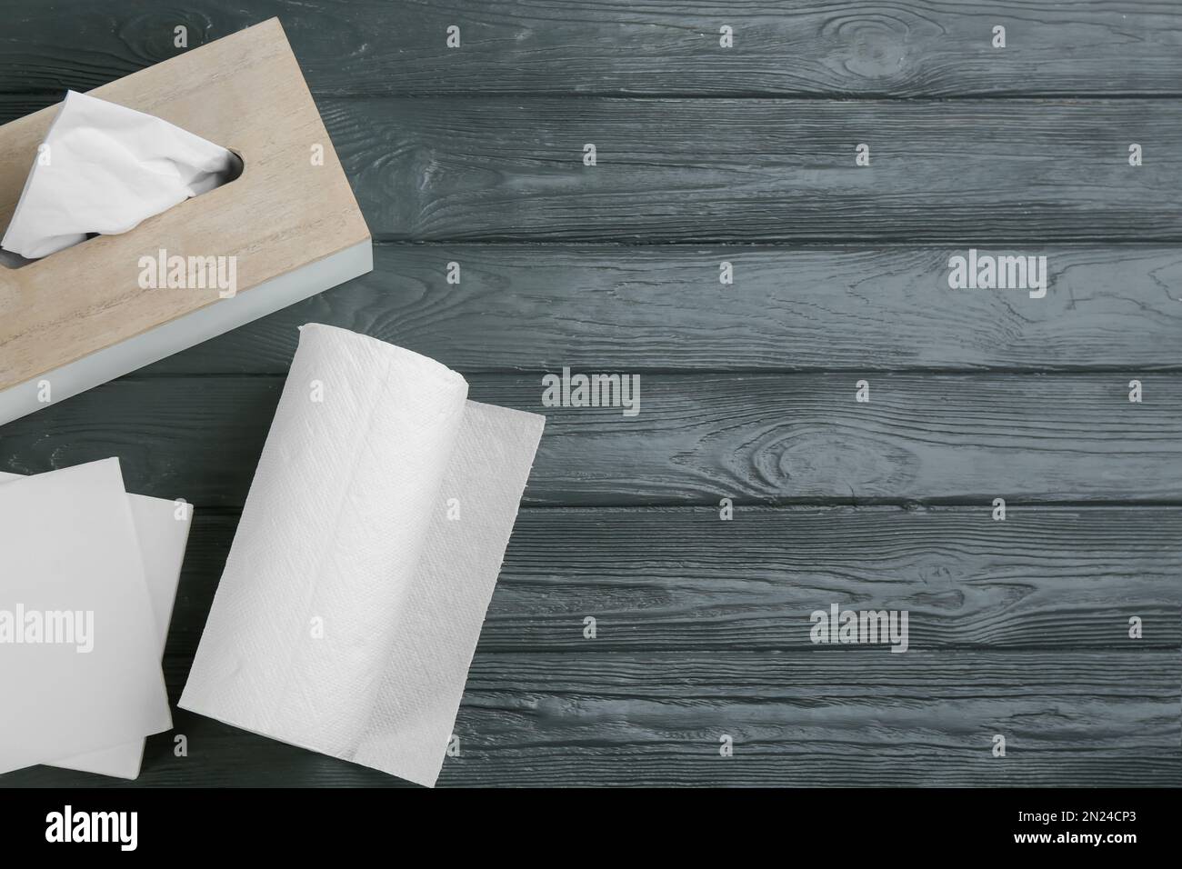 Nettoyer les serviettes, la boîte avec des mouchoirs et un rouleau d'essuie-tout sur une table en bois gris, poser à plat. Espace pour le texte Banque D'Images