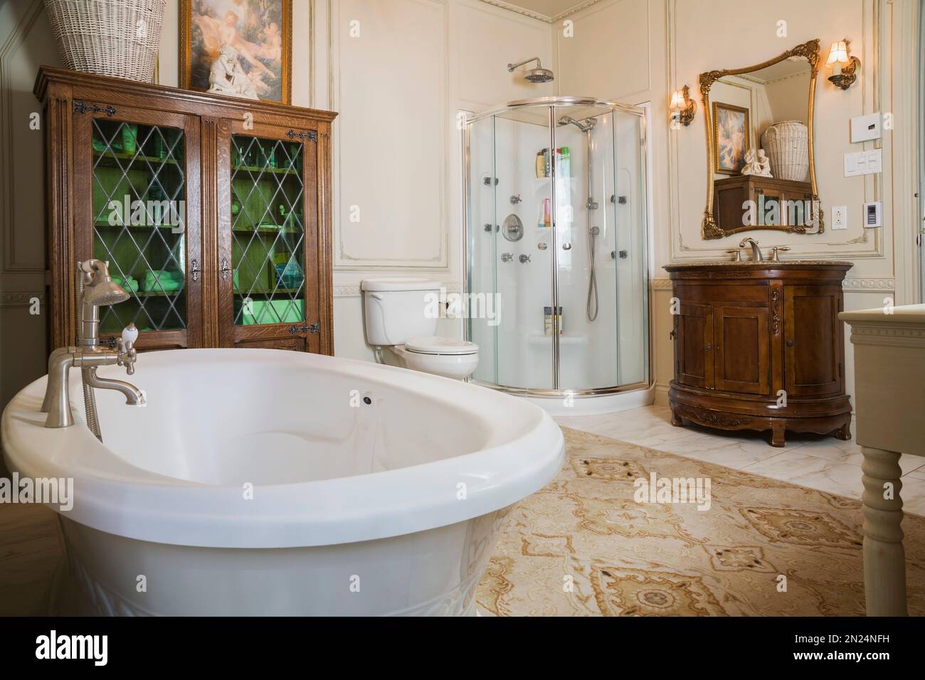 Baignoire autoportante de style bateau, cabine de douche en verre et meuble-lavabo en bois dans la salle de bains principale à l'étage à l'intérieur de la maison de style Renaissance. Banque D'Images