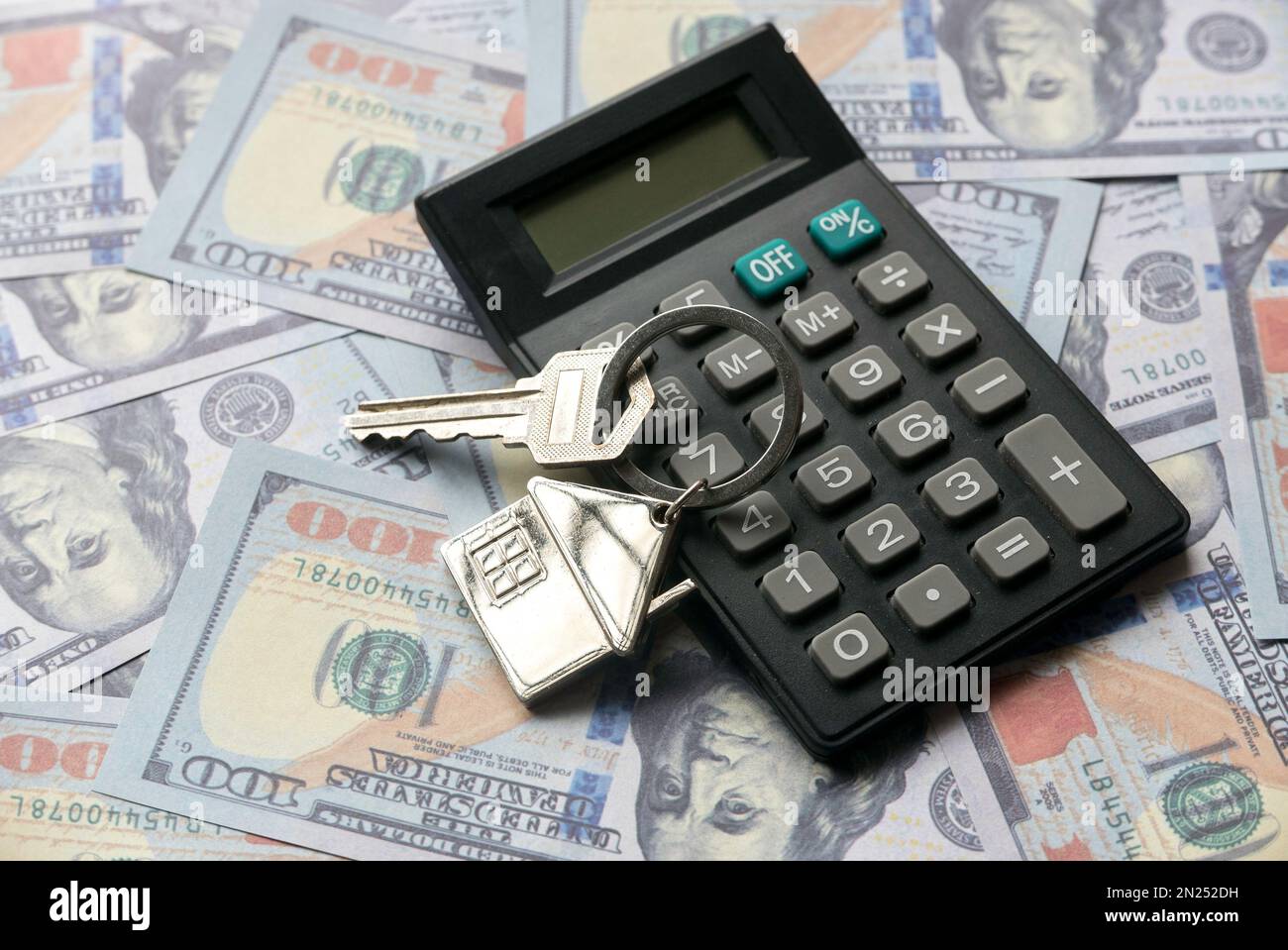 Une calculatrice et une clé maison sur un dollar d'argent ou des billets de banque. Banque D'Images