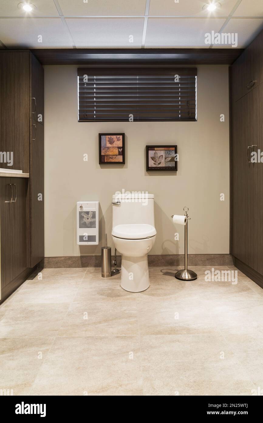 meubles de toilette en porcelaine blanche et en bois brun dans la buanderie salle de bains au sous-sol à l'intérieur d'une petite maison. Banque D'Images