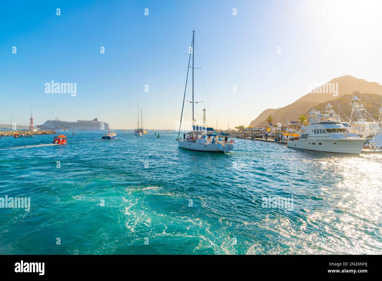 Des bateaux de pêche, des yachts et des voiliers partent en mer avec un grand bateau de croisière en vue au port de Cabos San Lucas, au Mexique, le long de la Riviera mexicaine. Banque D'Images