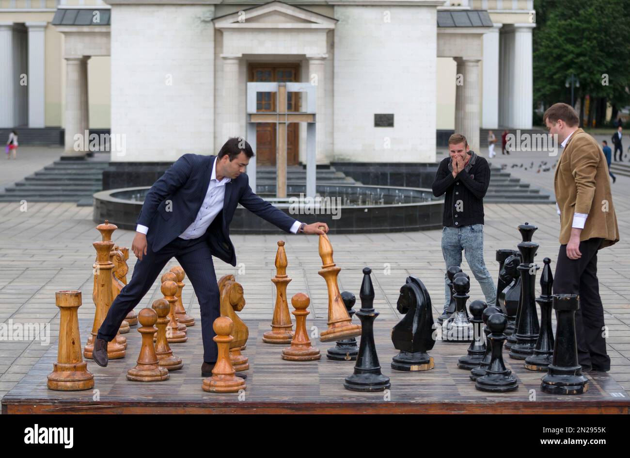 In this Thursday, May 28, 2015 photo, a man laughs as others play chess with oversized pieces on a public entertainment board, in Chisinau, Moldova. The chess game is a popular pastime in parks around the capital. Most players use their own chessboards. (AP Photo/Vadim Ghirda) Banque D'Images