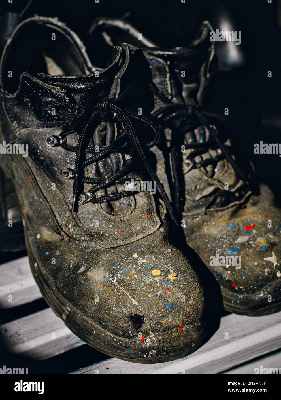 Chaussures de travail. Vieilles bottes colorées et bottes de peintre industriel usées. Arrière-plan... Banque D'Images