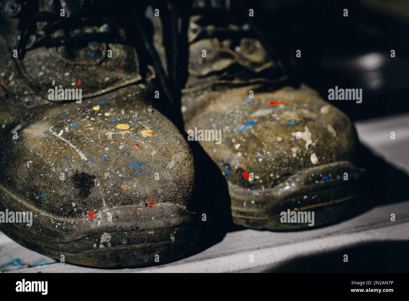 Chaussures de travail. Vieilles bottes colorées et bottes de peintre industriel usées. Arrière-plan... Banque D'Images