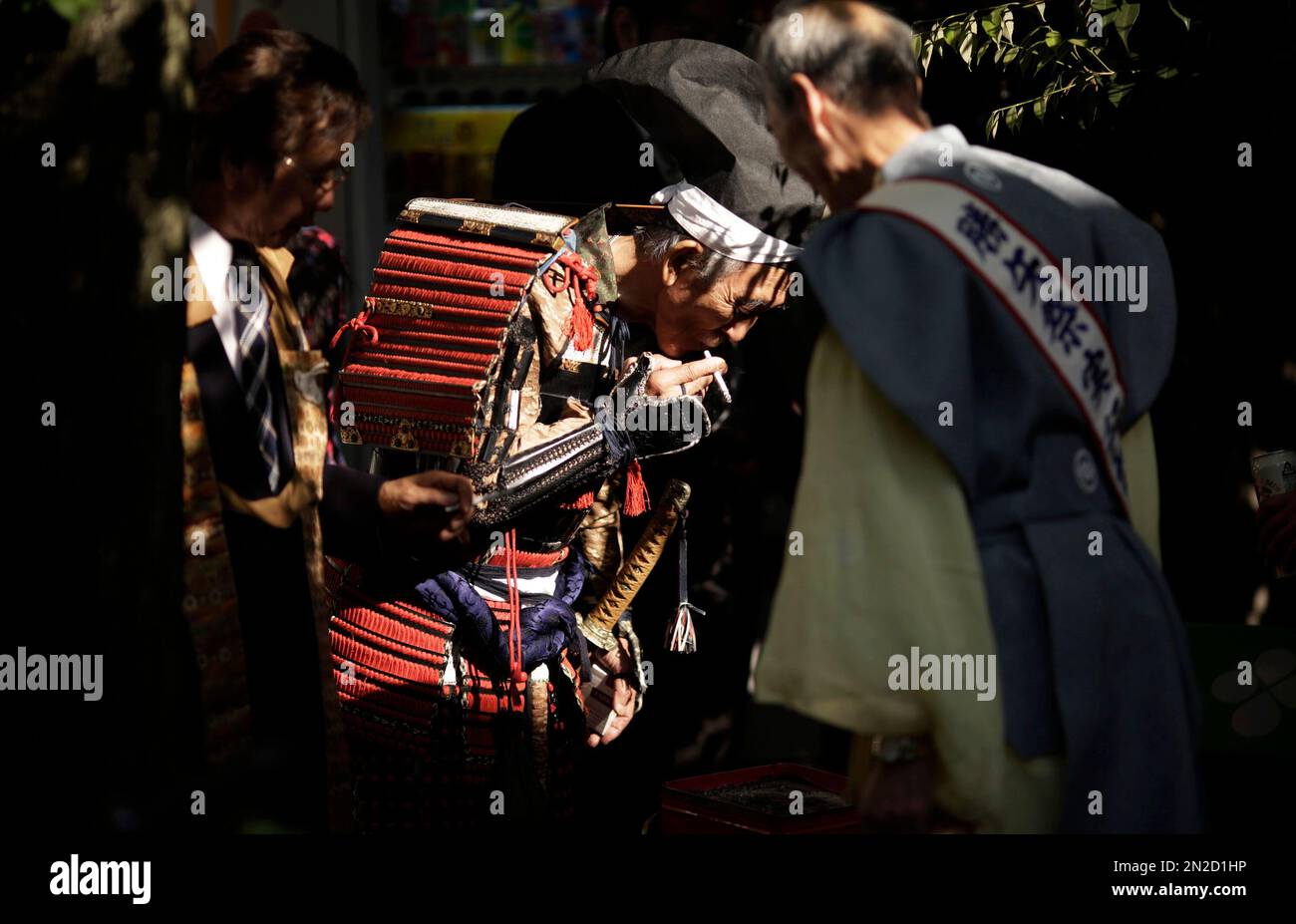 A man dressed as a samurai warrior in armor smokes after the Kachiya Festival at Katori Shrine in Tokyo, Tuesday, May 5, 2015. The festival celebrates that the warlord Fujiwara Hidesato made for victory over warlord Taira no Masakado's revolt in 940 during the Heian Period (794-1185) and then, Fujiwara dedicated a "kachiya" or victory arrow to the shrine. (AP Photo/Eugene Hoshiko) Banque D'Images