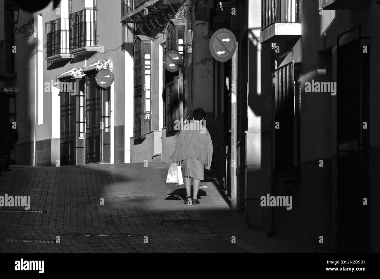 Femme sur la rue solitaire venant de shopping avec des sacs en plastique, Nijar, Andalousie, Espagne Banque D'Images