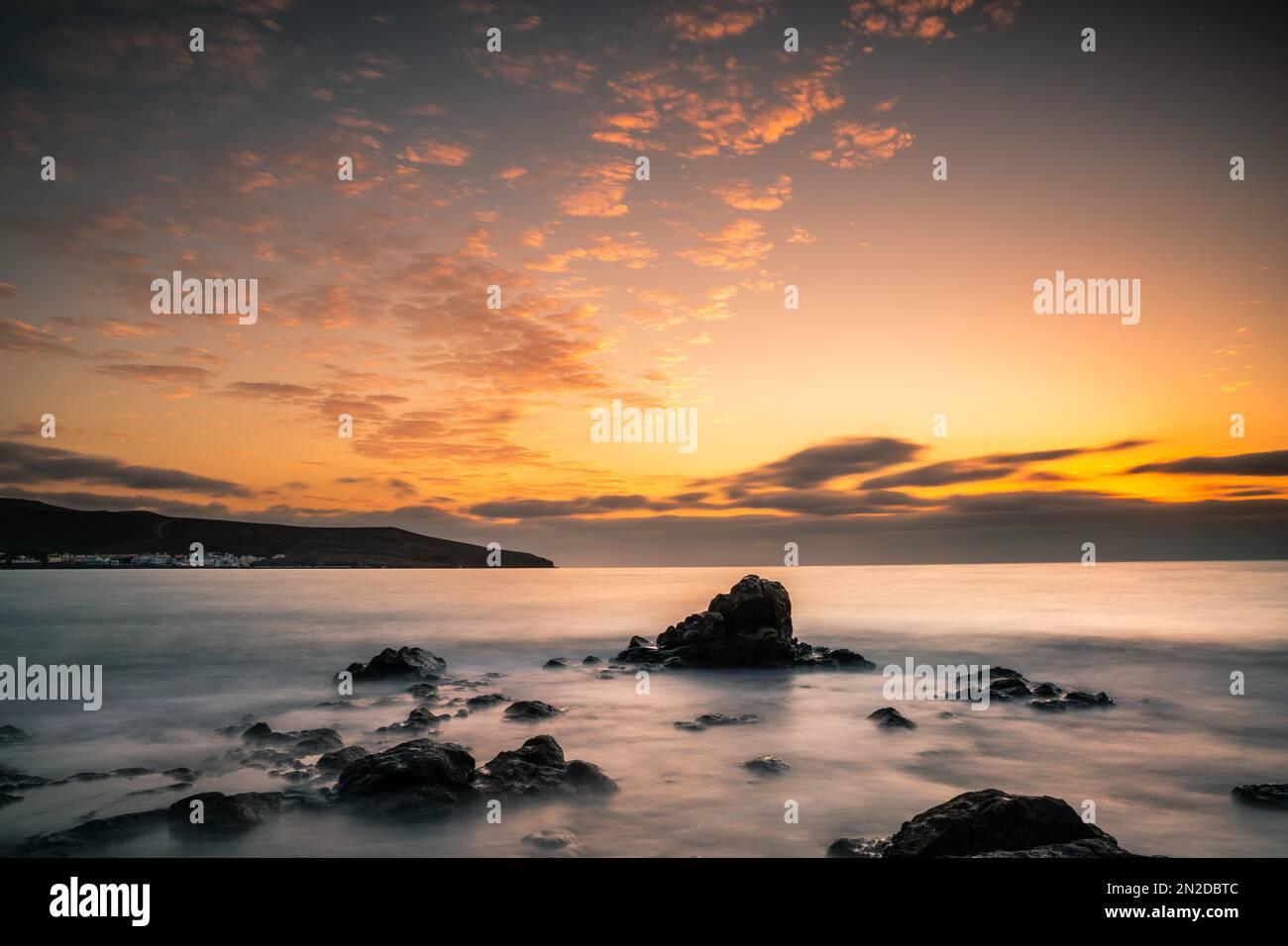 Lever du soleil, au-dessus de la mer dans une baie rocheuse, nuages, longue exposition, contre-jour, roche volcanique, Fuerteventura, Îles Canaries, Espagne Banque D'Images