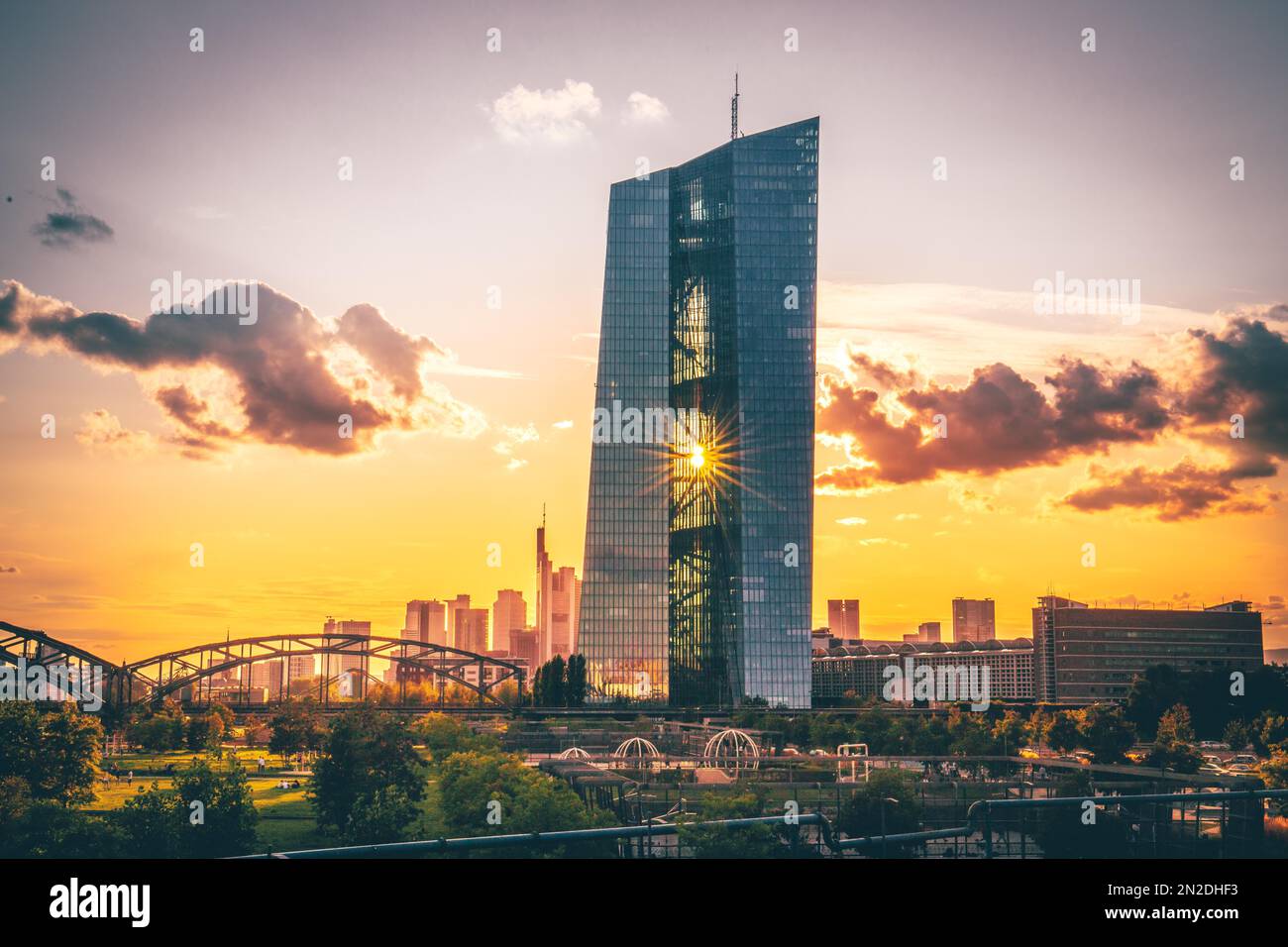 La Banque centrale européenne (BCE), à l'heure d'or, reflète le soleil dans la façade de verre et les rayons de soleil du pont Ignatz Bubis Banque D'Images