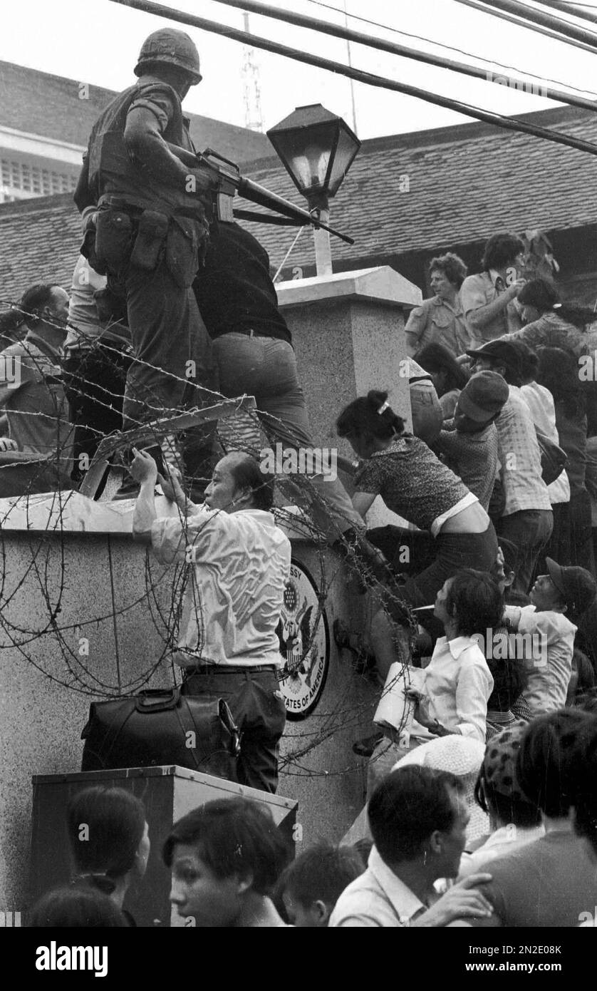 FILE - In this April 29, 1975 file photo, people try to scale the 14-foot wall of the U.S. embassy in Saigon, trying to reach evacuation helicopters, as the last of the Americans depart from Vietnam. (AP Photo/Neal Ulevich, File) Banque D'Images