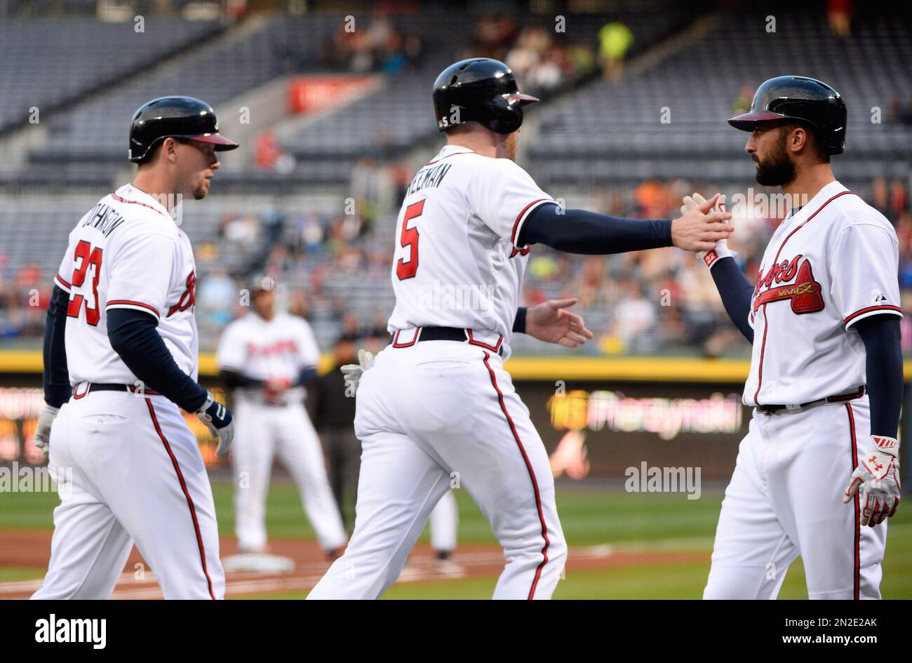 Atlanta Braves' Nick Markakis, right, welcomes Freddie Freeman (5) after they score against the Washington Nationals on a single by AJ Pierzynski, while Chris Johnson (23) waits to hit during the first inning of a baseball game Wednesday, April 29, 2015, in Atlanta. (AP Photo/David Tulis) Banque D'Images