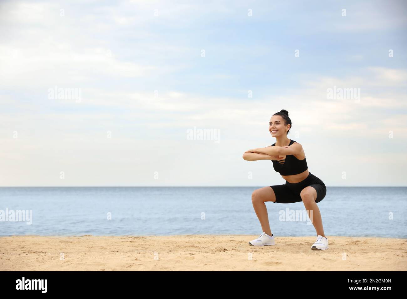 Jeune femme faisant de l'exercice sur la plage, espace pour le texte. Entraînement du corps Banque D'Images