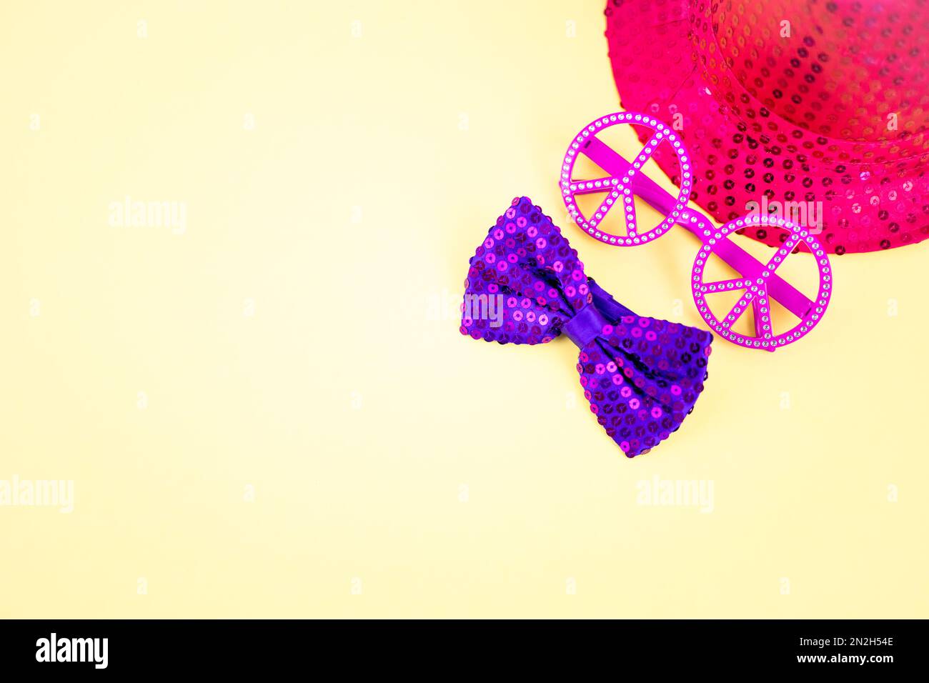 Fond jaune de carnaval avec lunettes de paix roses isolées et chapeau à paillettes et noeud papillon violet. Costume d'accessoires coloré pour le festival et la fête. Banque D'Images