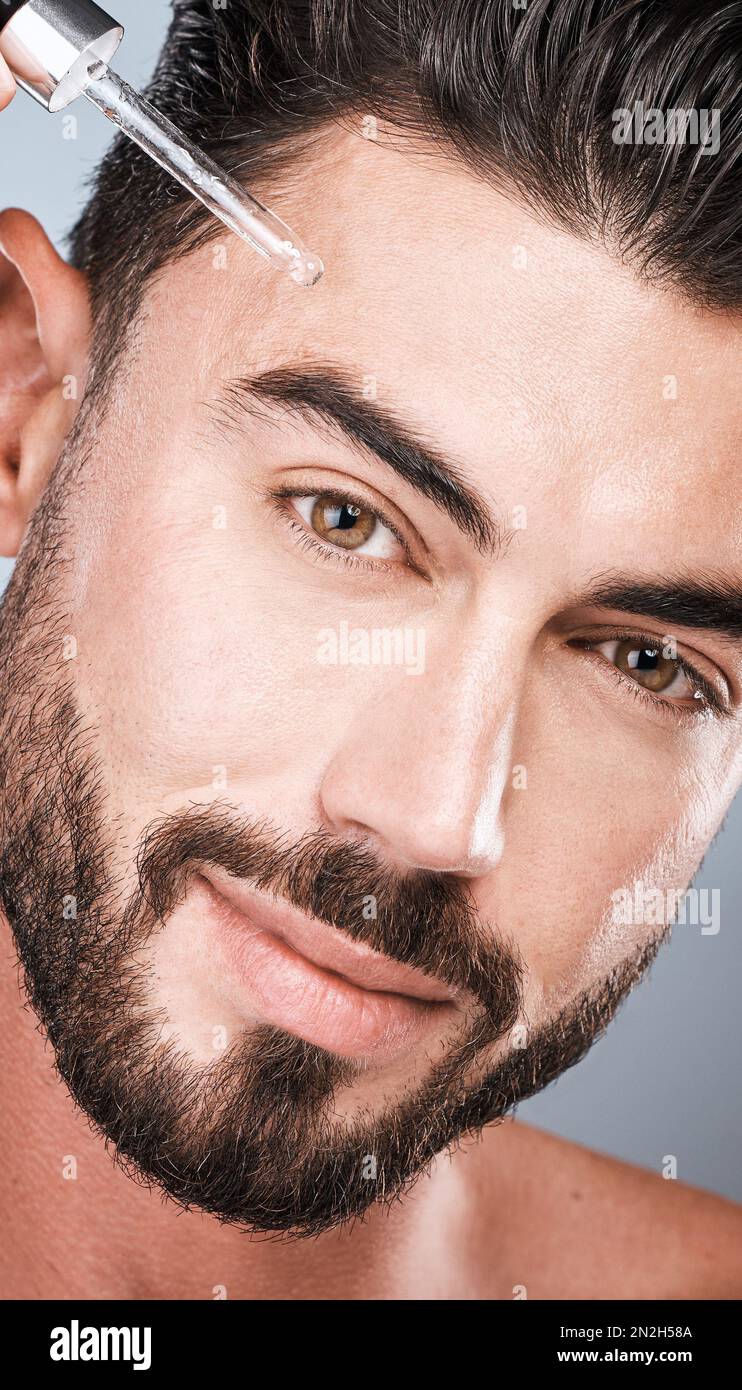 Beauté, huile et homme avec pipette pour les soins de la peau, l'auto-soin et le traitement pour une peau éclatante ou lisse isolée dans un fond gris studio. Portrait, visage et Banque D'Images